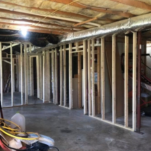 Construction site with exposed wooden framing and ductwork in progress inside a building.