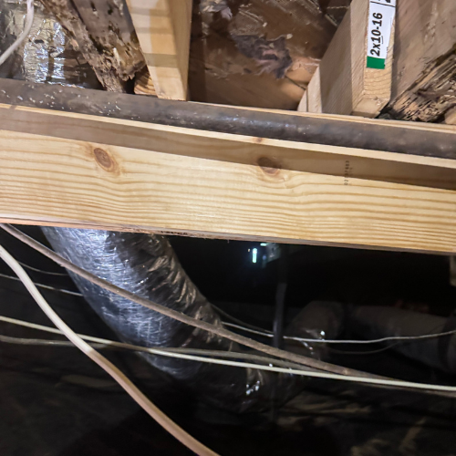 View of ceiling joists and ductwork in an attic space with insulation and electrical wiring.