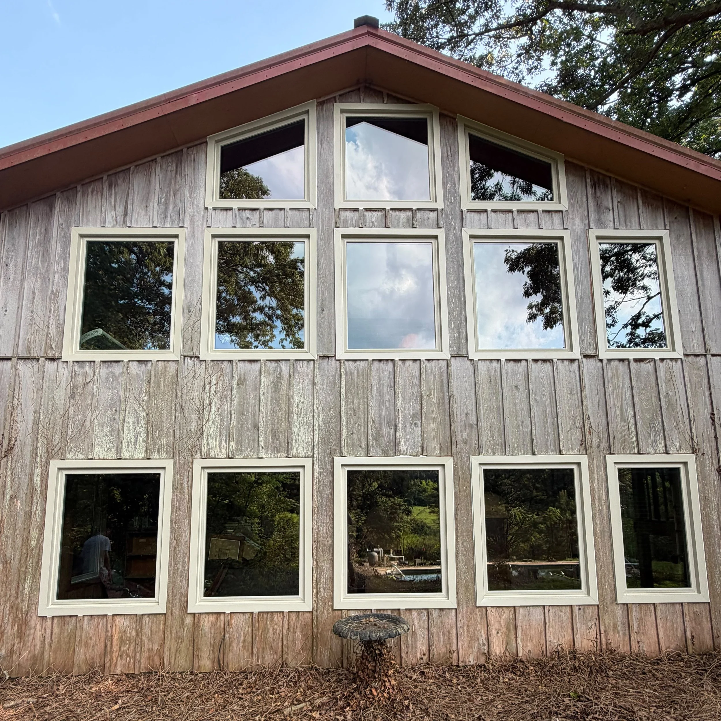 Multiple replacement windows installed across a wood-clad façade