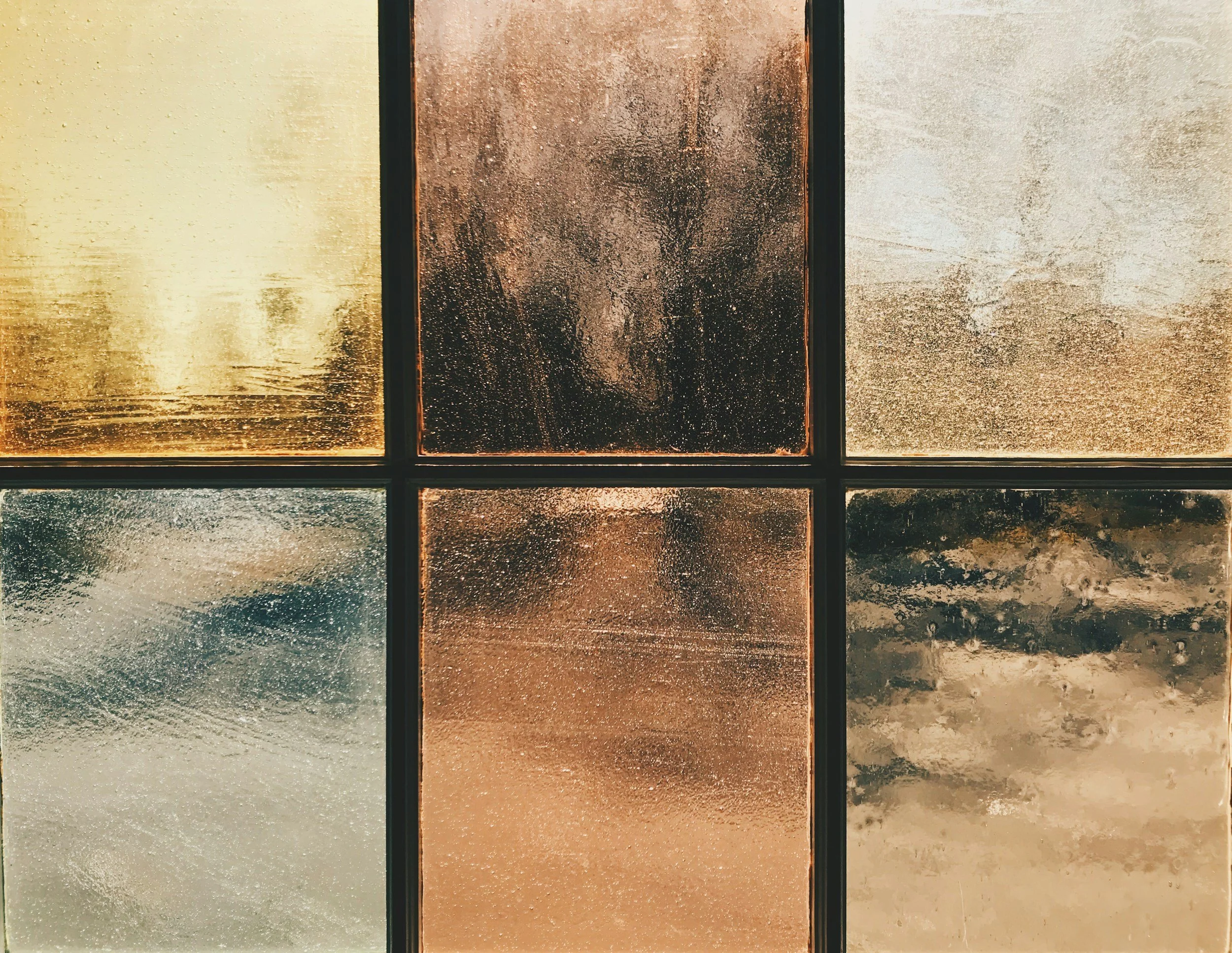 Close-up view of six textured and colored glass panels arranged in a grid, with varied colors including gold, copper, bronze, and silver.