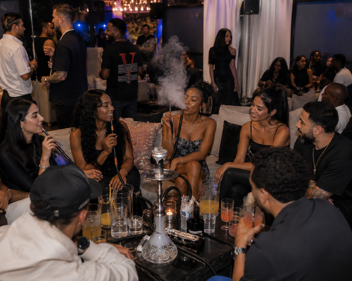 Group of friends sitting around a table smoking hookah, with drinks on the table, in a social setting.