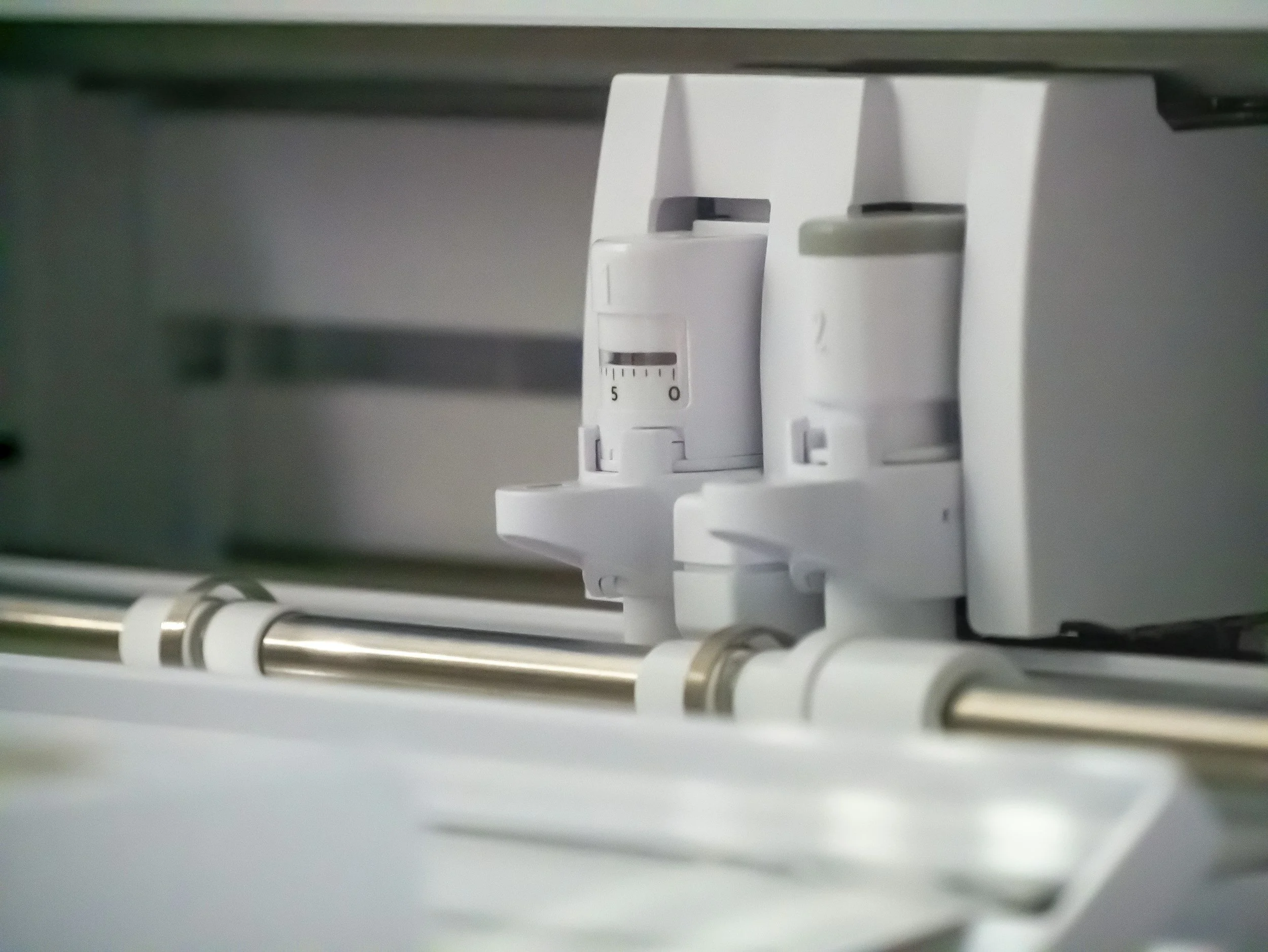 Close-up of a white laboratory or medical equipment with dials and metallic tubes.