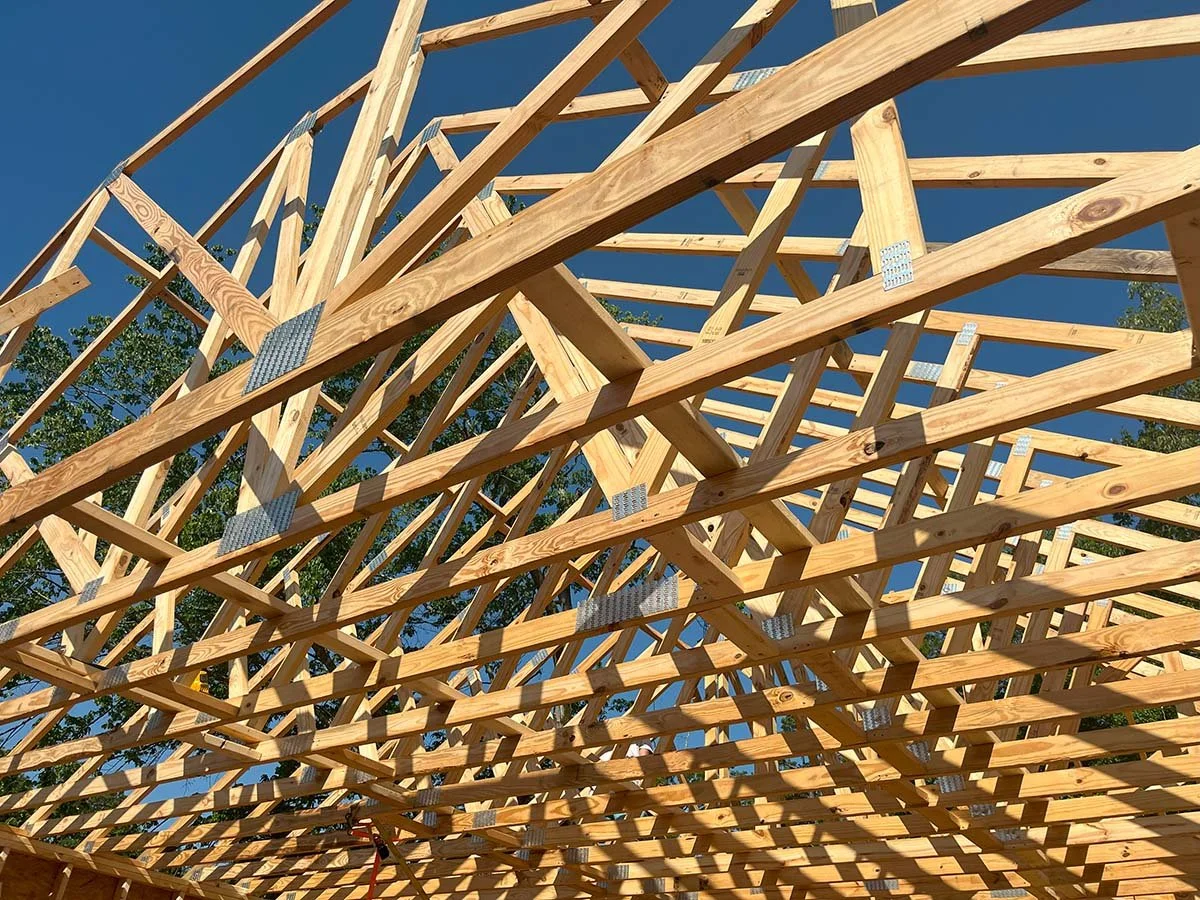 View of a wooden building structure under construction with a clear blue sky in the background.