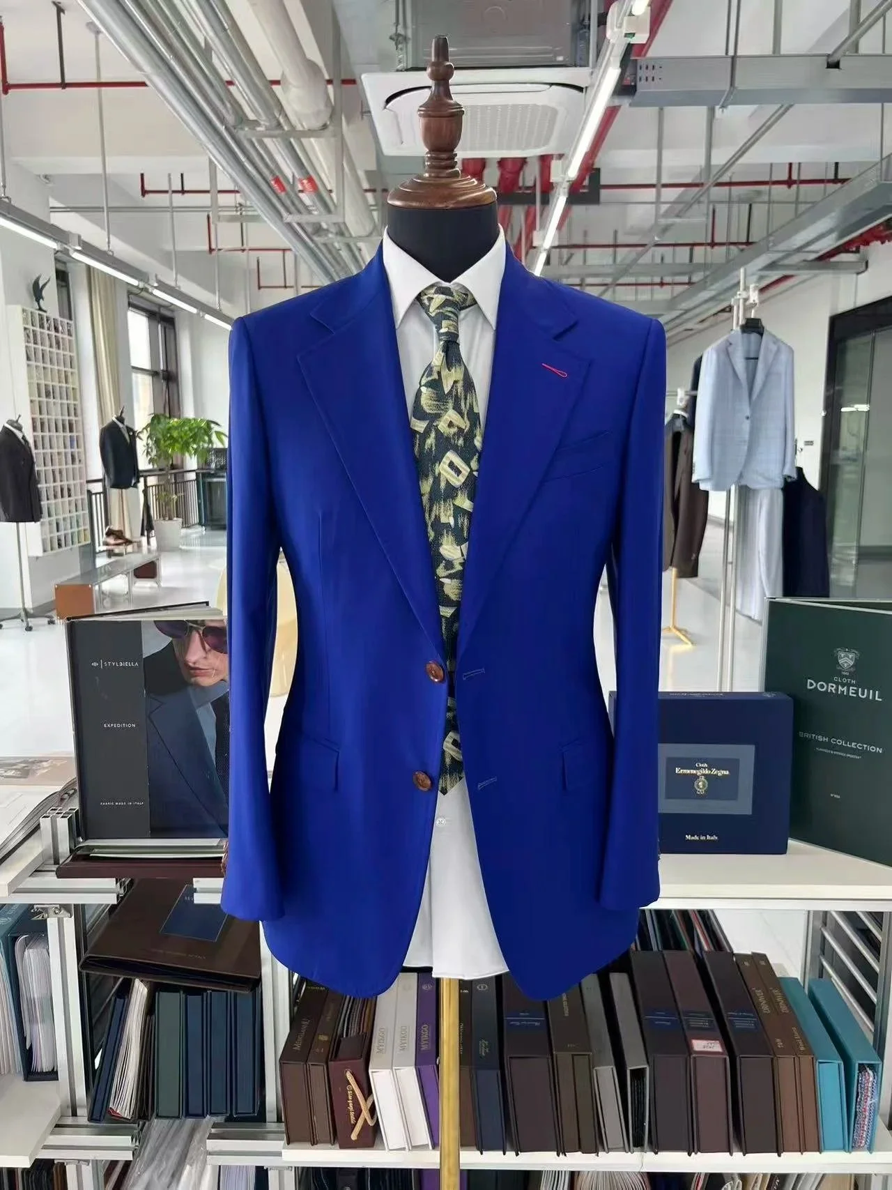 A mannequin dressed in a blue suit jacket, white dress shirt, and a patterned tie, displayed in a clothing store.