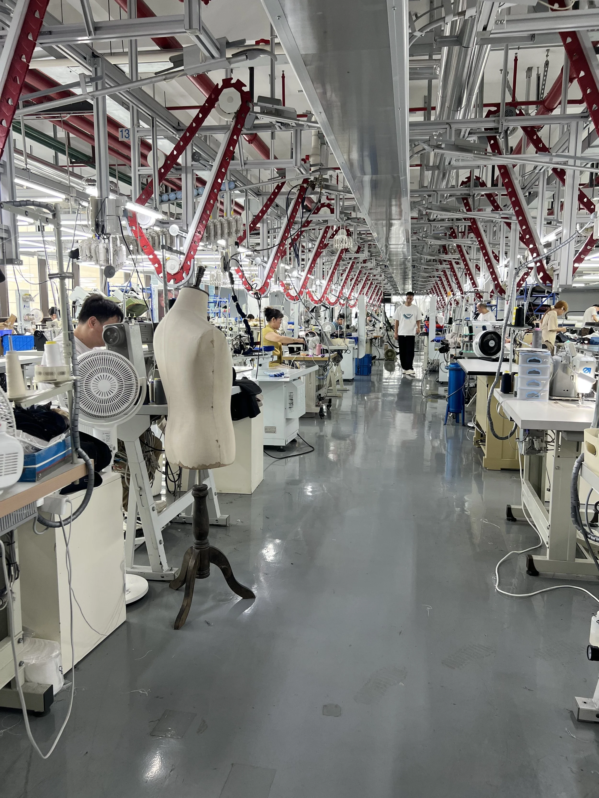 Manufacturing factory with workers and machinery for sewing or assembling textiles.