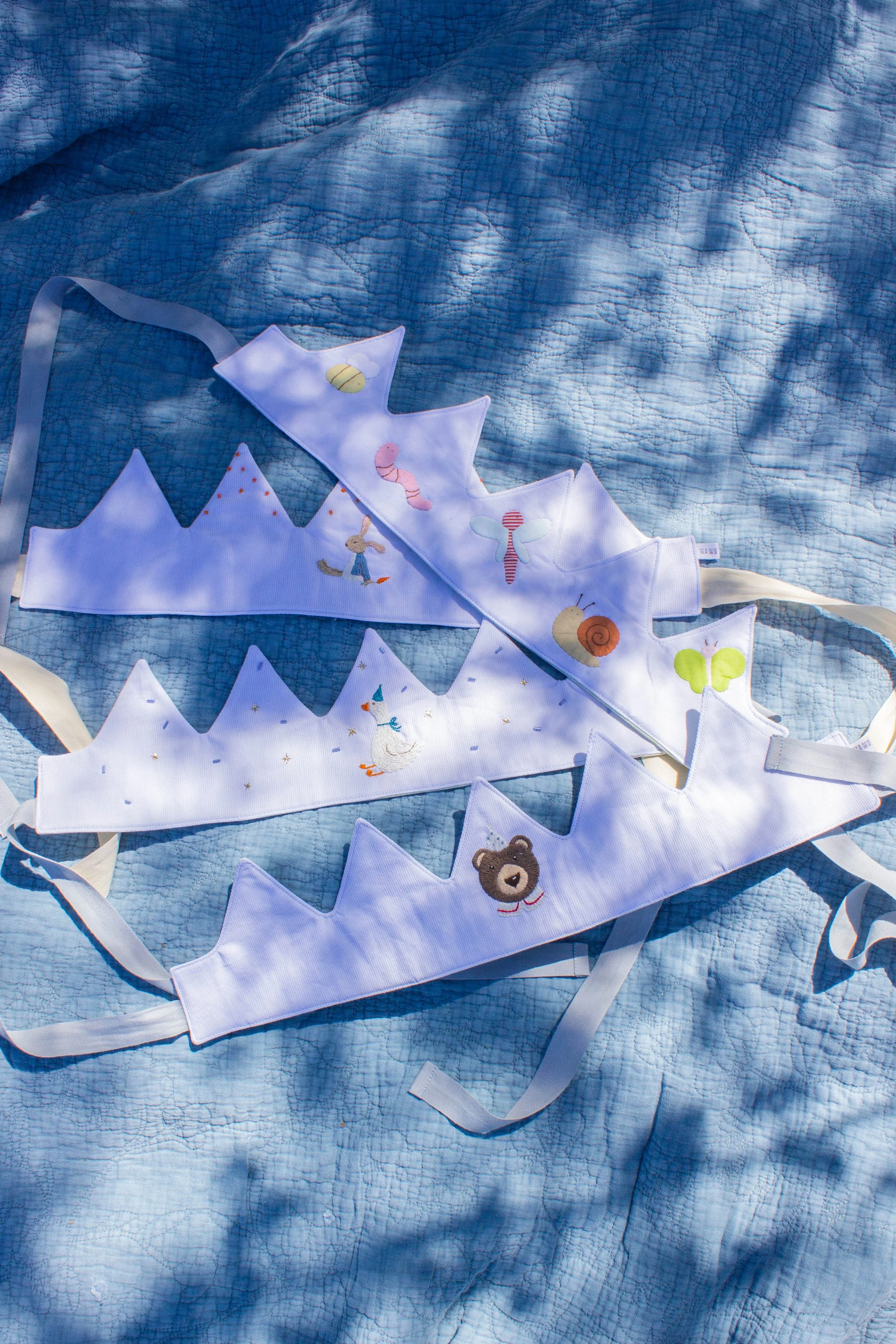 Colorful fabric banner with embroidered animal and nature-themed designs lying on a blue quilted surface.