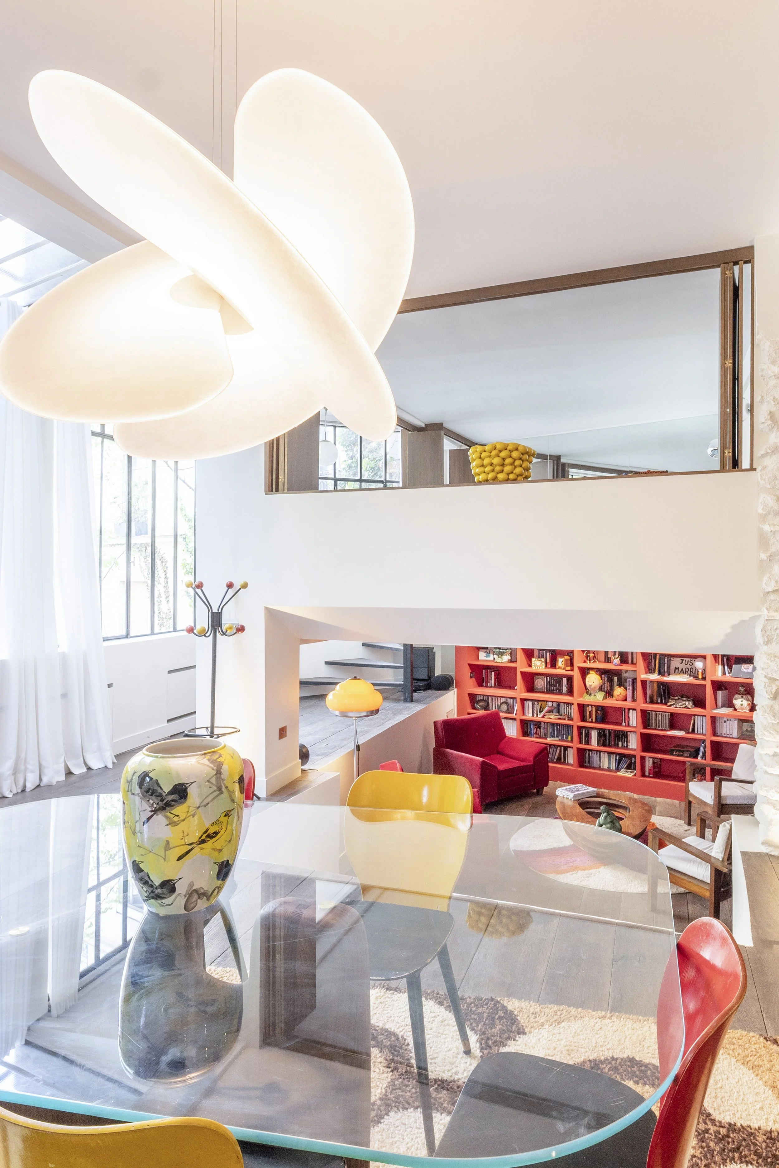 Espace de vie en duplex avec suspension design, salle à manger et bibliothèque intégrée à Lamarck Caulaincourt par DMM Interiors.