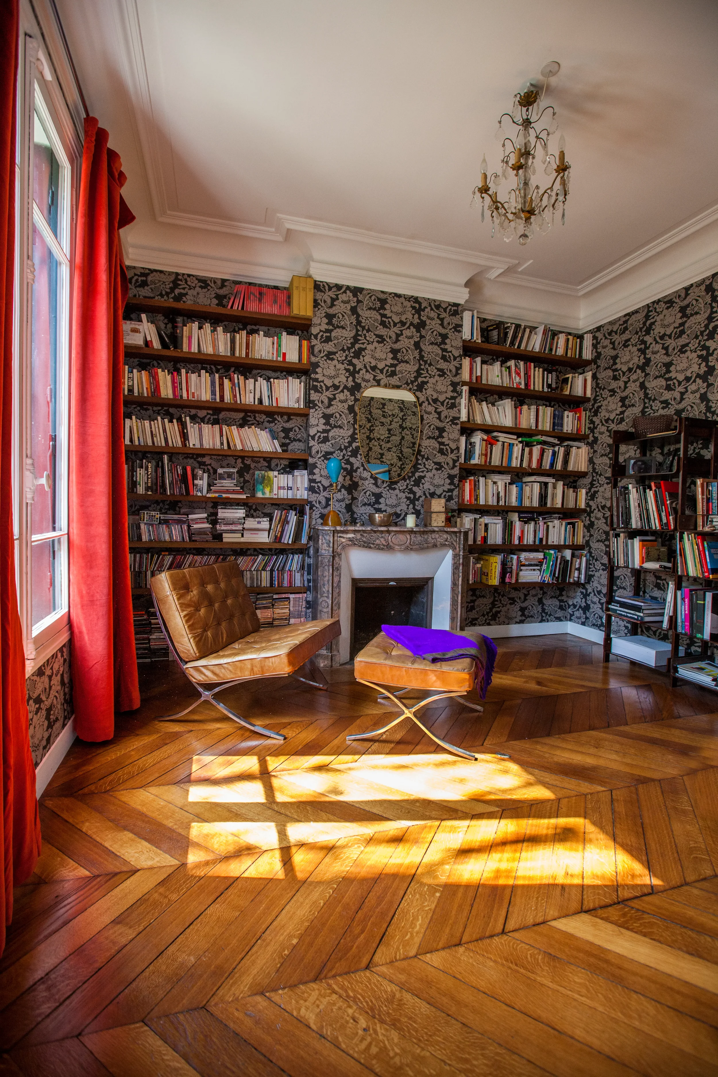 Salon haussmannien avec parquet Point de Hongrie, bibliothèque sur-mesure et fauteuil Barcelona, projet Cantona par DMM Interiors.