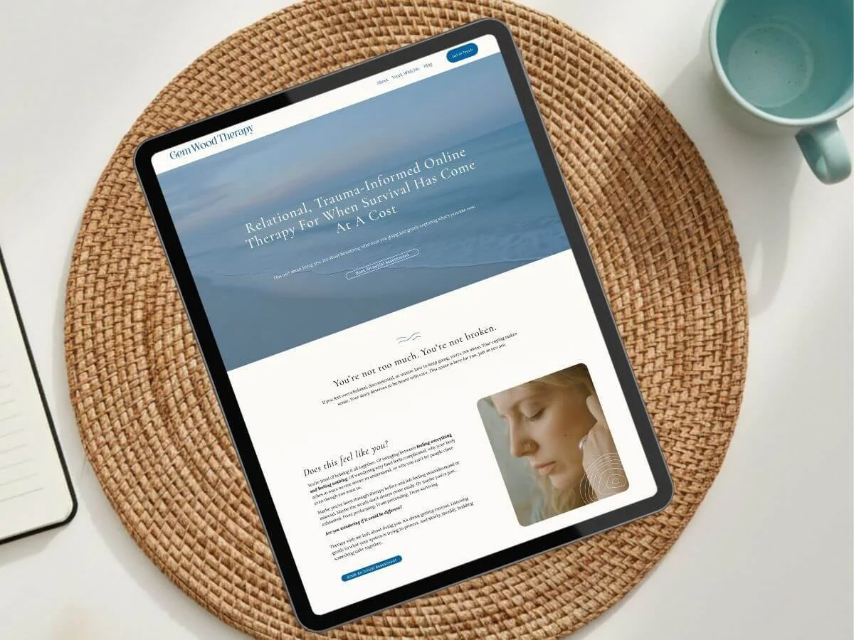 Tablet displaying a website about trauma-informed online therapy, placed on a woven placemat with a mug nearby.