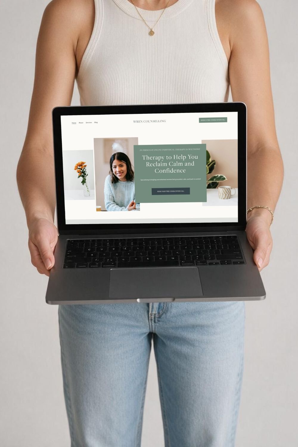 Person holding a laptop displaying a counseling service website with a photo of a woman smiling and text about therapy to help reclaim calm and confidence.