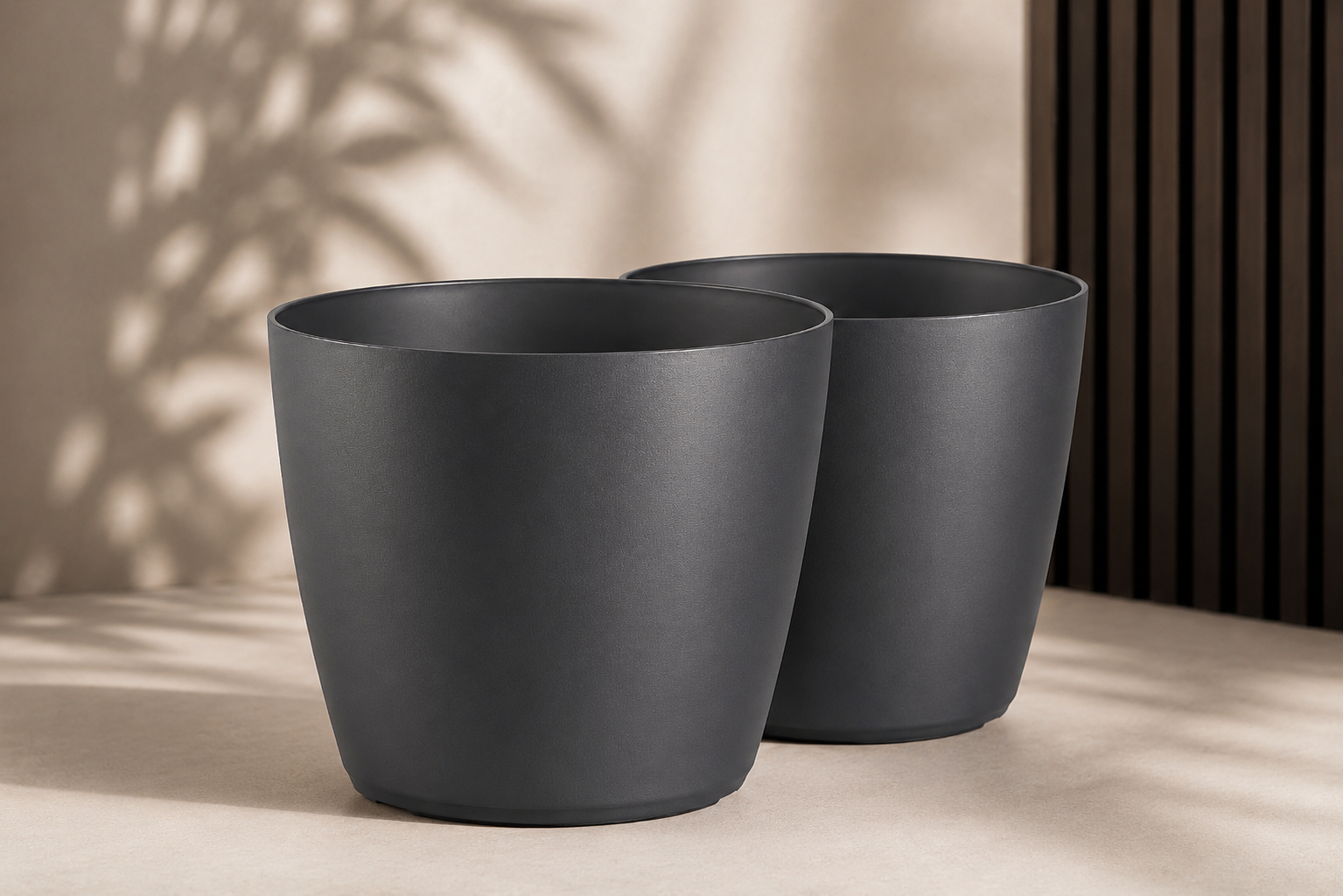 Schwarze Pflanzkübel in unterschiedlichen Grössen für eine moderne Terrasse mit klaren, zeitlosen Outdoor-Akzenten.
