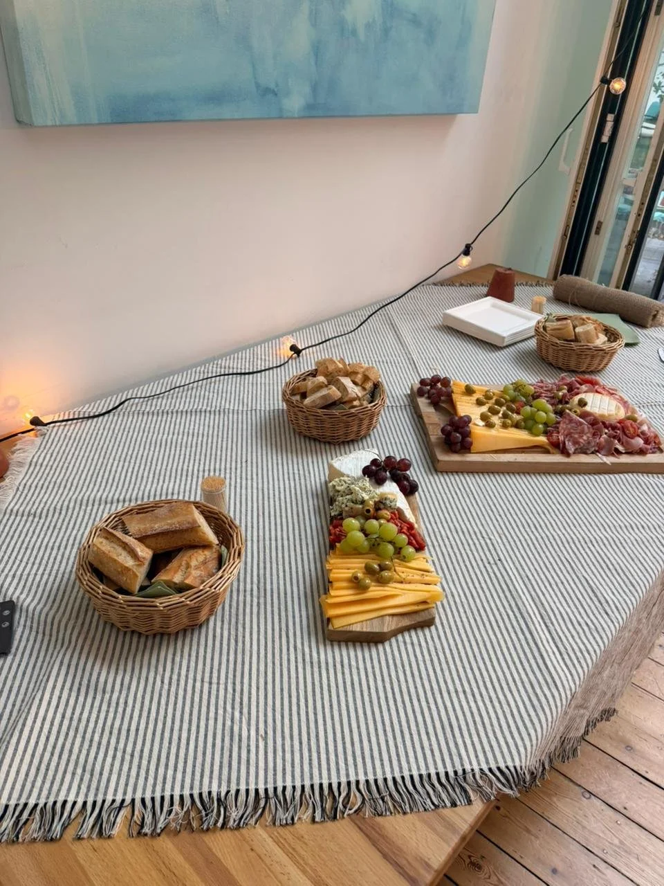 Cheese and fruit platter with bread and charcuterie on a table.