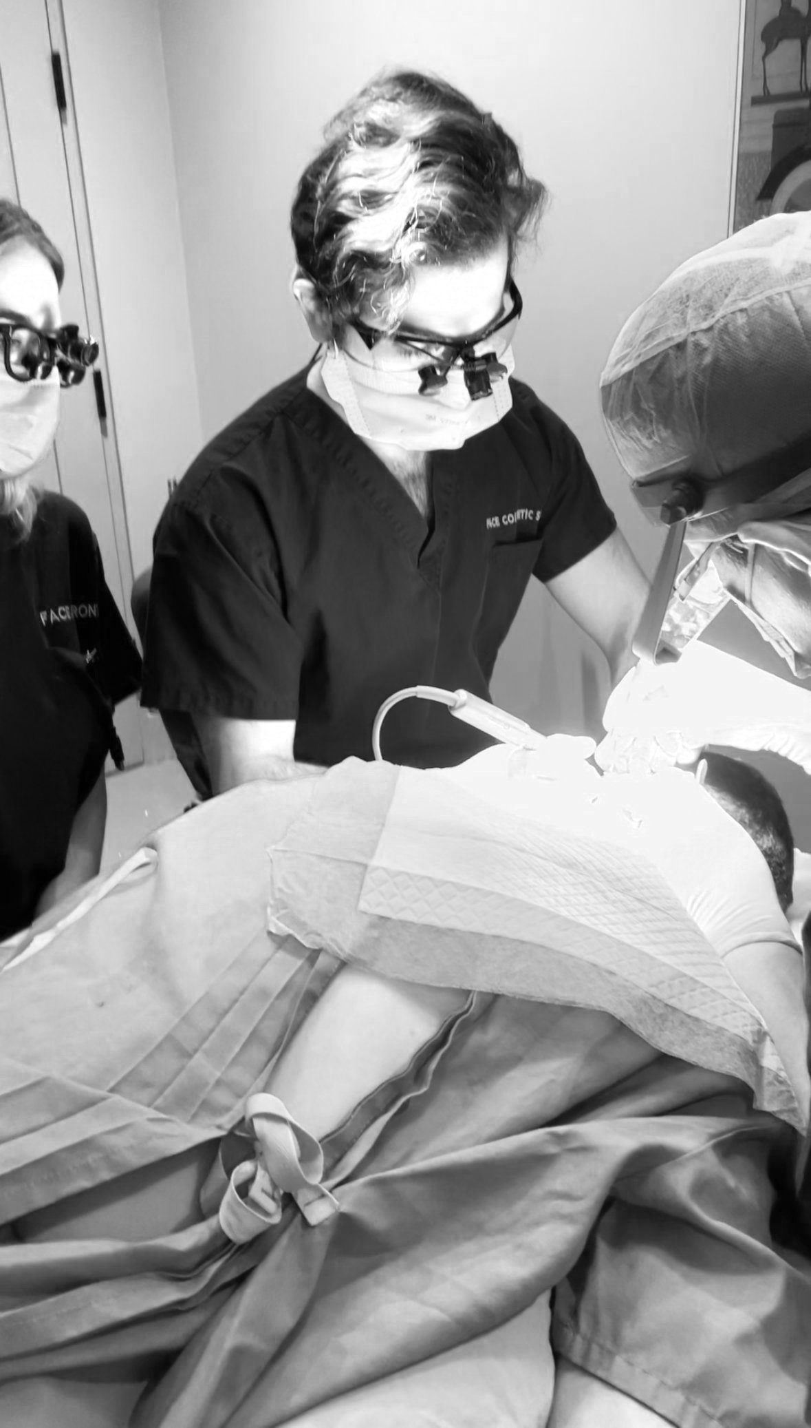 Medical professionals performing surgery in a sterile environment, focusing on a patient on the operating table.