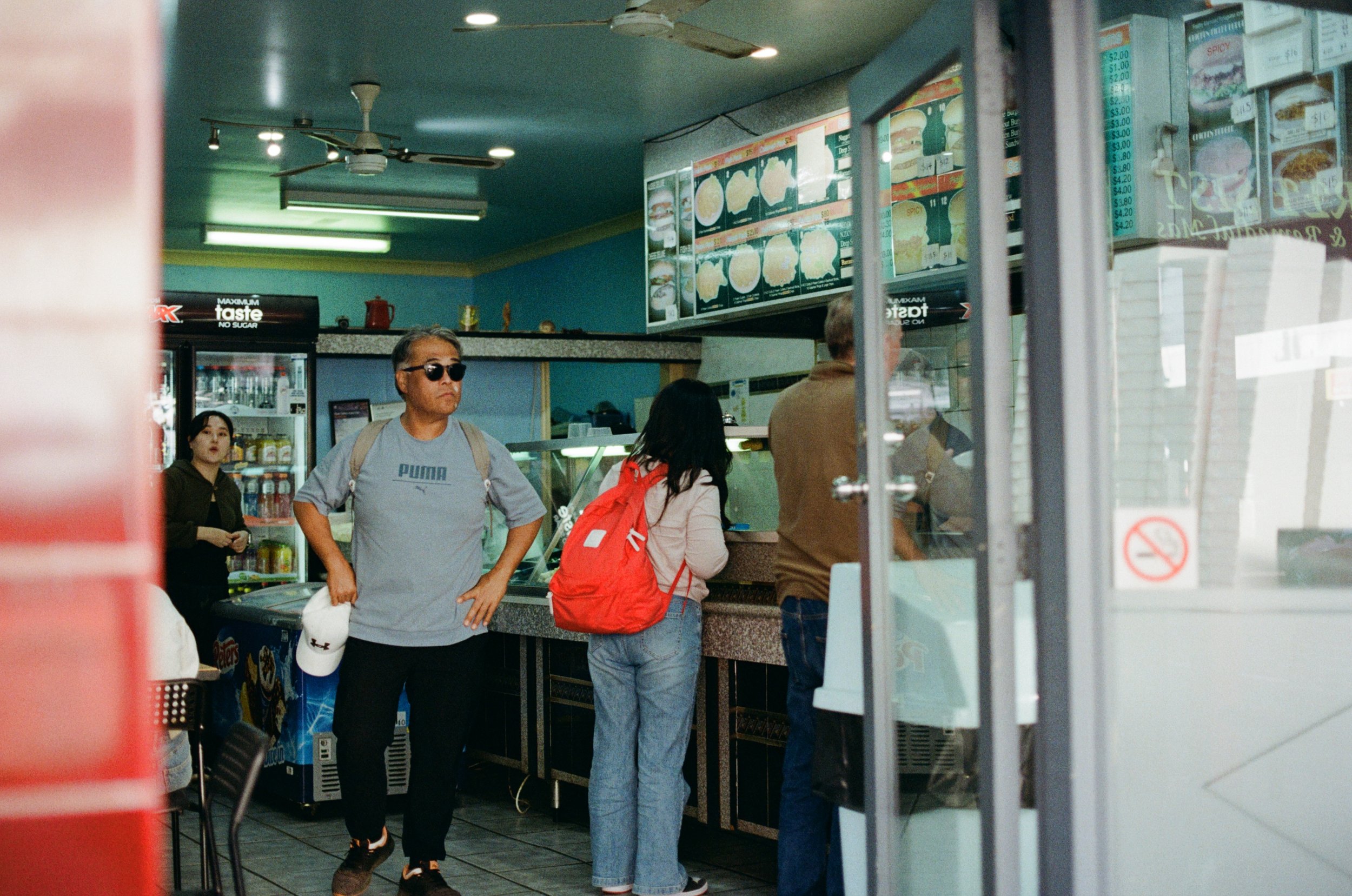 People inside a fast food restaurant ordering at the counter, with menu boards overhead displaying food options.