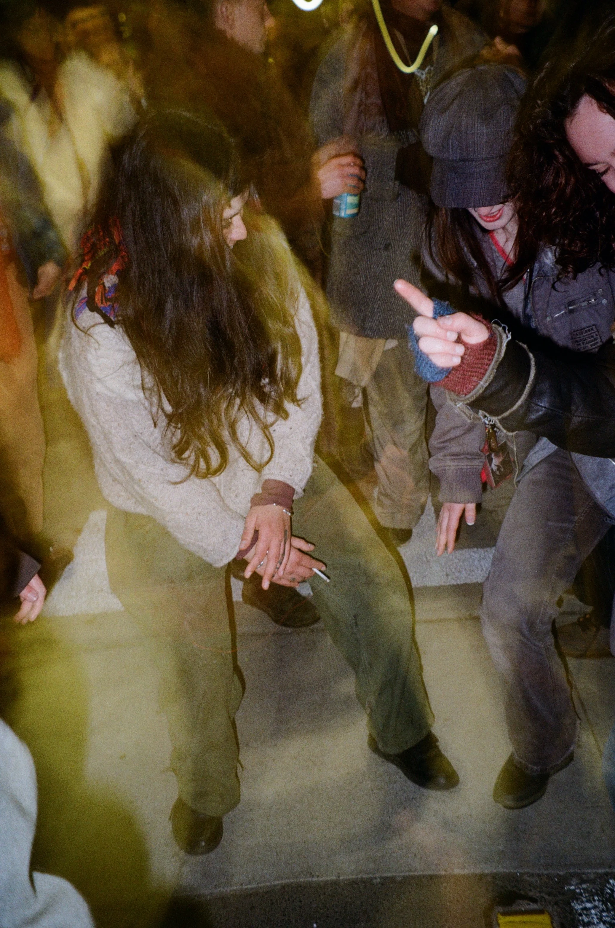 A group of people standing close together, with only their lower bodies and legs visible in the photo. They are wearing casual, warm clothing including boots, jeans, and jackets.