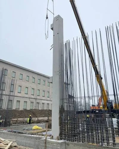 Opere in corso con un grattacielo in costruzione, con operai e gru presente.