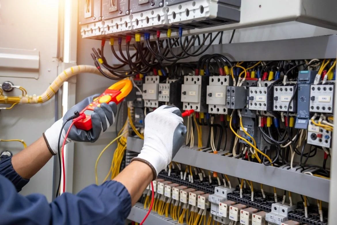 Tecnico che lavora su un pannello elettrico con strumenti di diagnosi