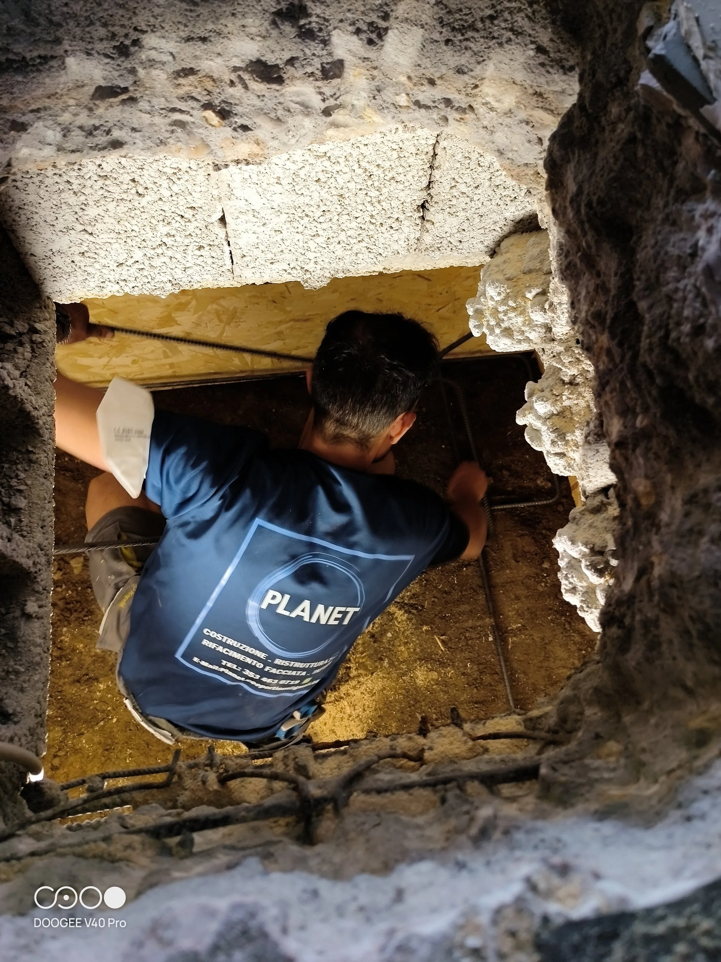 Persona che lavora in un caveau o sotto terra, vista attraverso una fessura tra le rocce o il cemento.