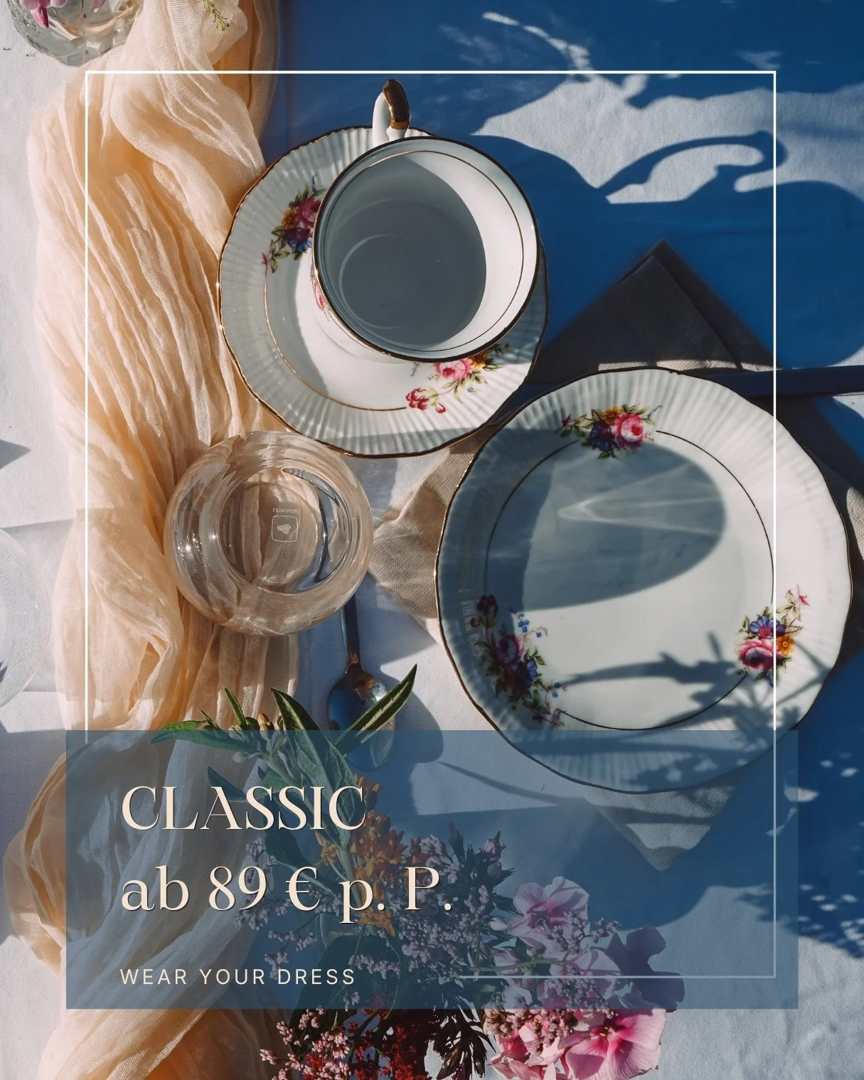Eleganter gedeckter Tisch mit vintage Geschirr, Wasser im Glas, Tasse und Tellern mit Blumenmuster, Samt- und Stoffstoffe, verbunden mit Blumen und Schatten im Tageslicht.