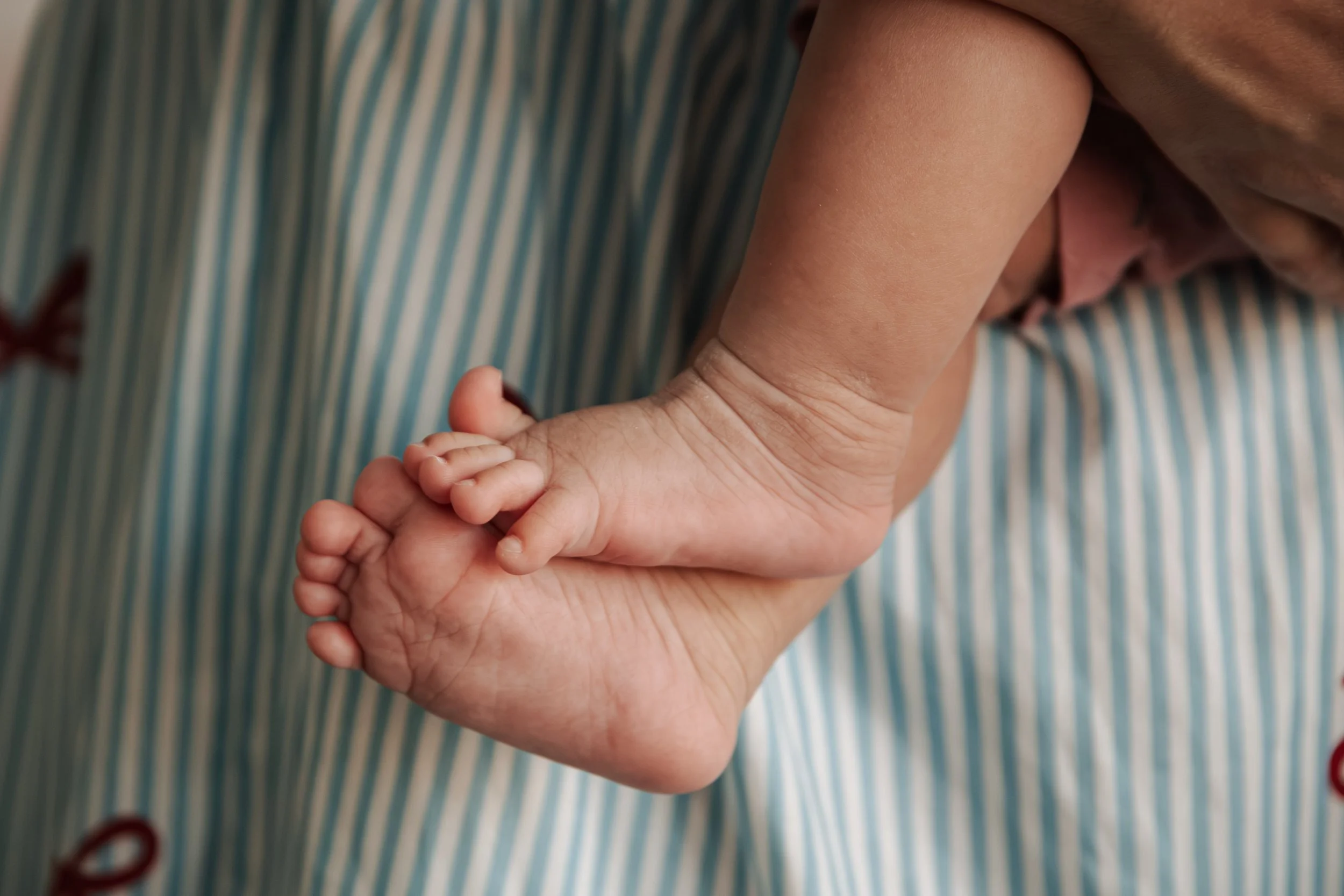 Close-up van een volwassene die een baby vasthoudt met de hand.