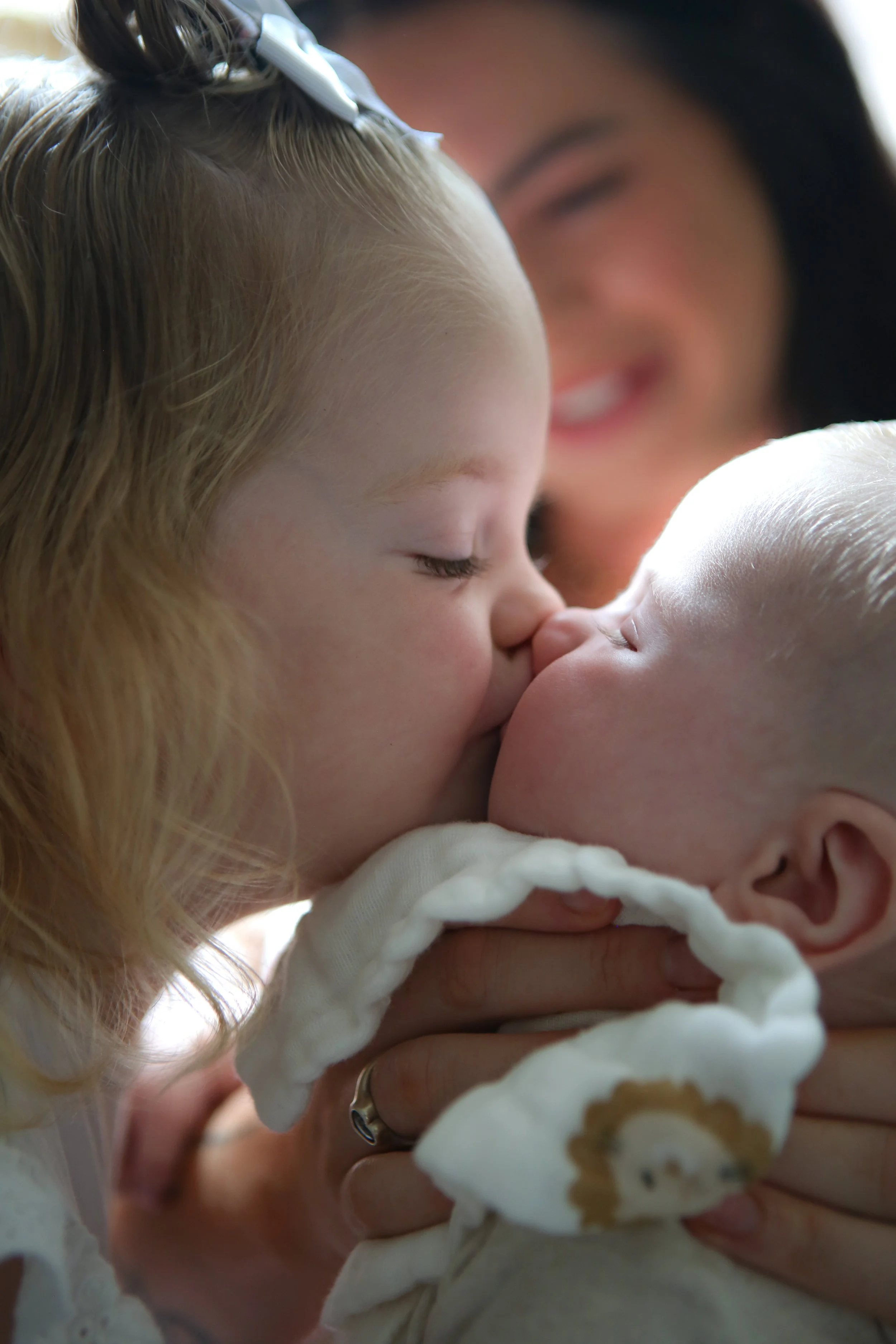 Liefhebbende moeder kussend haar pasgeboren baby, close-up van gezichten.