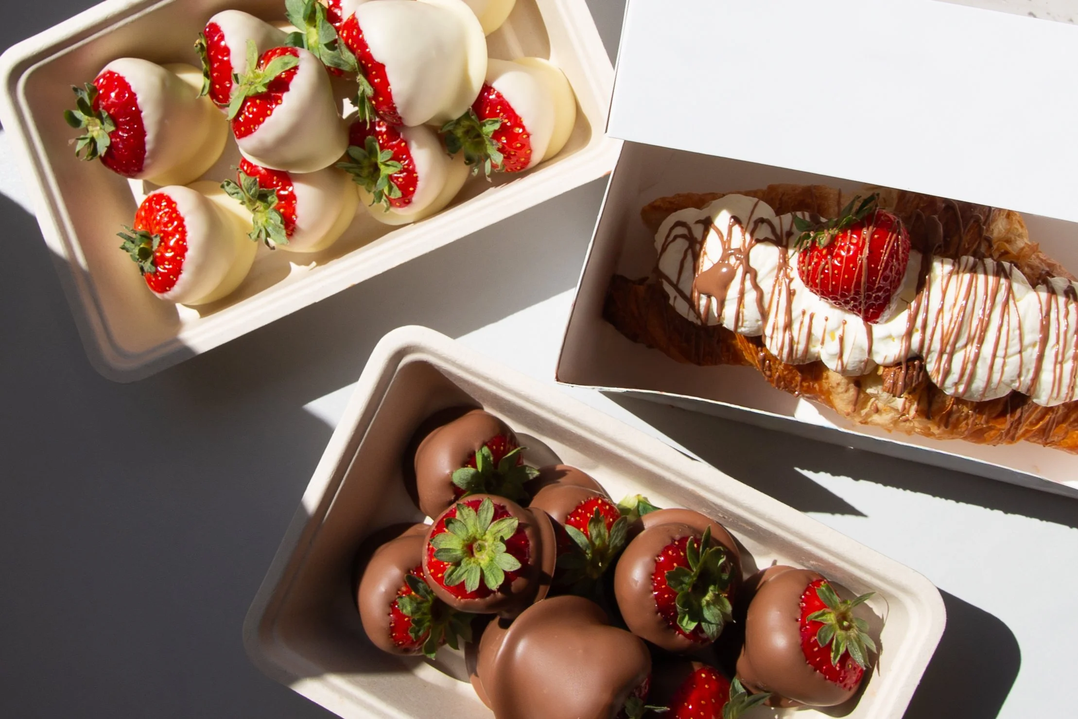 Diverse aardbeien en chocolade aardbeien in doosjes.