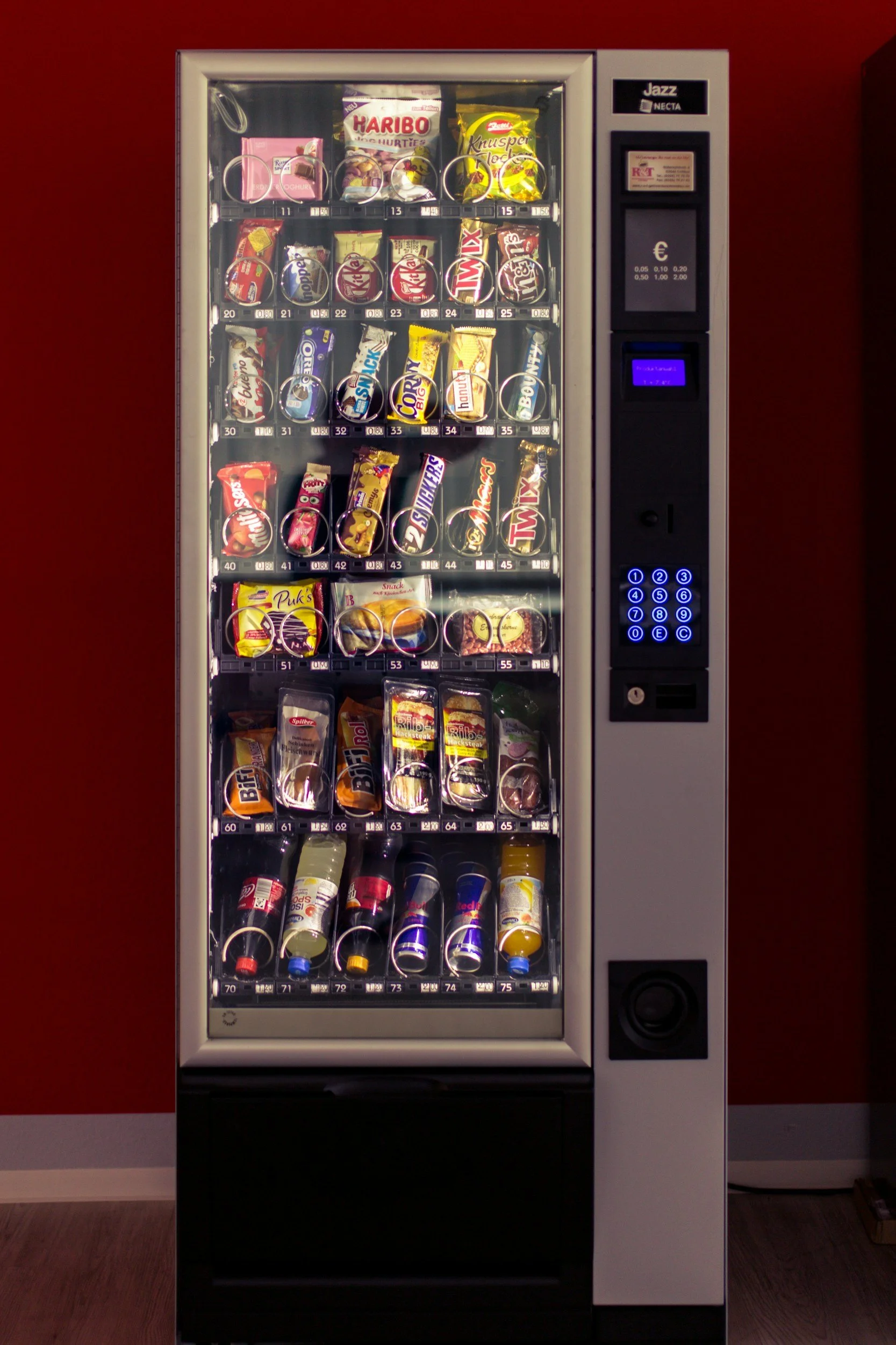 Vending machine filled with snacks and beverages, illuminated against a dark background.