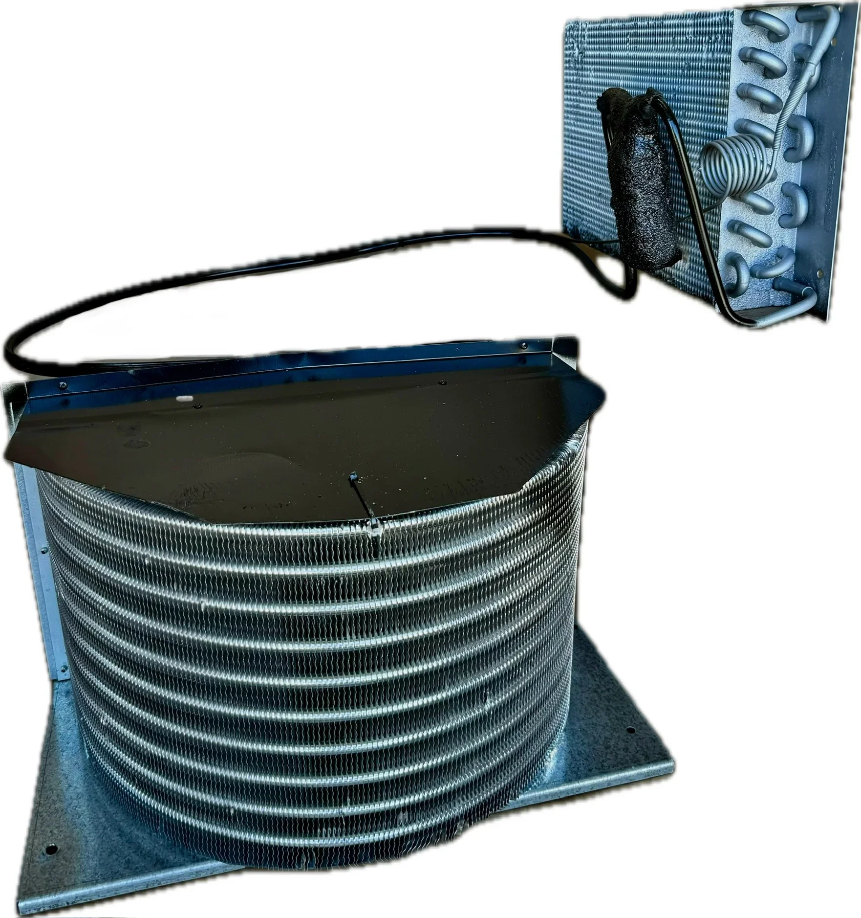 Close-up of a large industrial heat exchanger with metal coils and pipes, mounted on a base with protective grille.