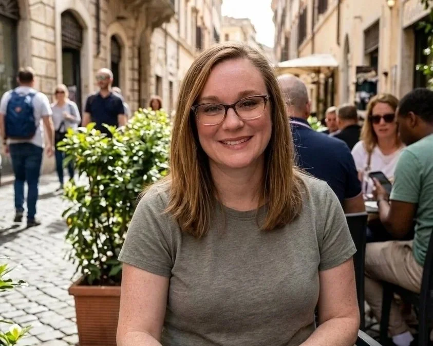 Niki Saul, owner of Together Travel at an outdoor cafe on a cobblestone street with people walking and sitting in the background.