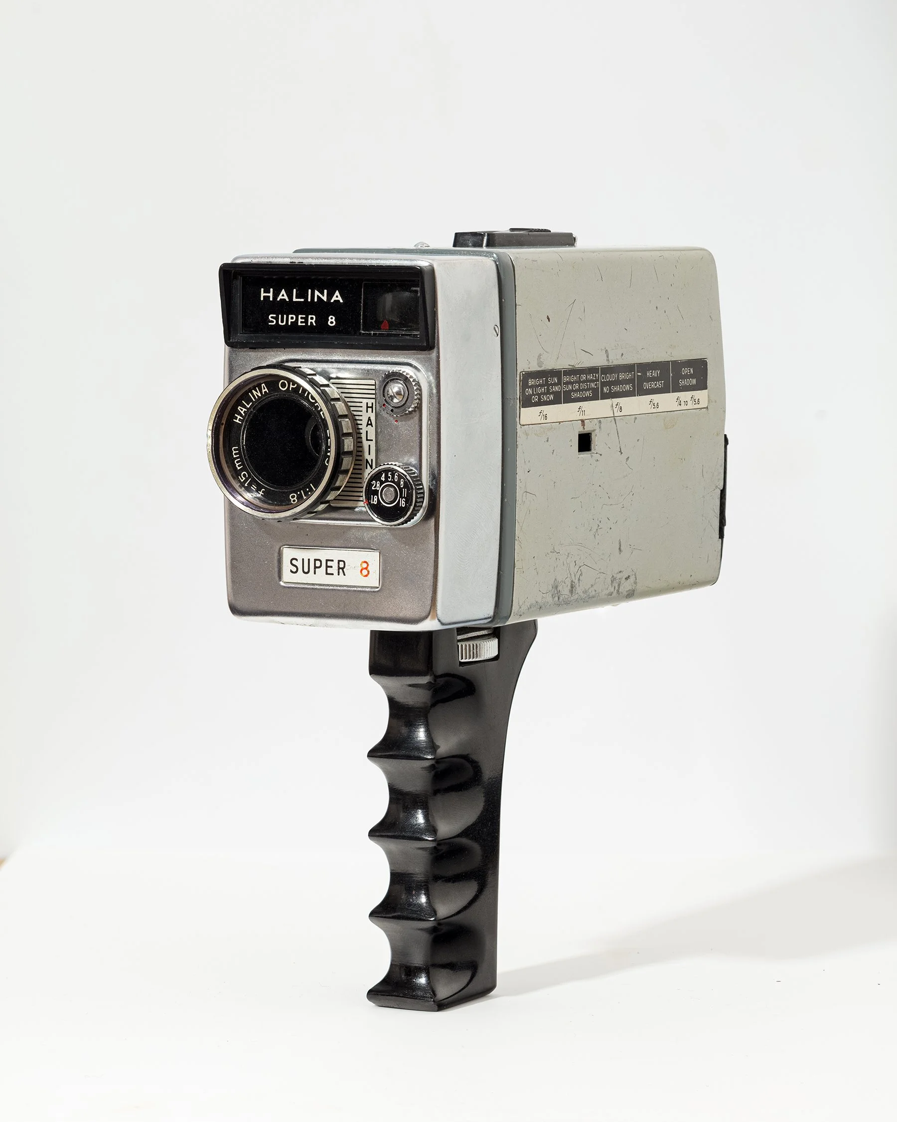 A vintage Halina Super 8 camera with a black handle and silver body, set against a plain white background.