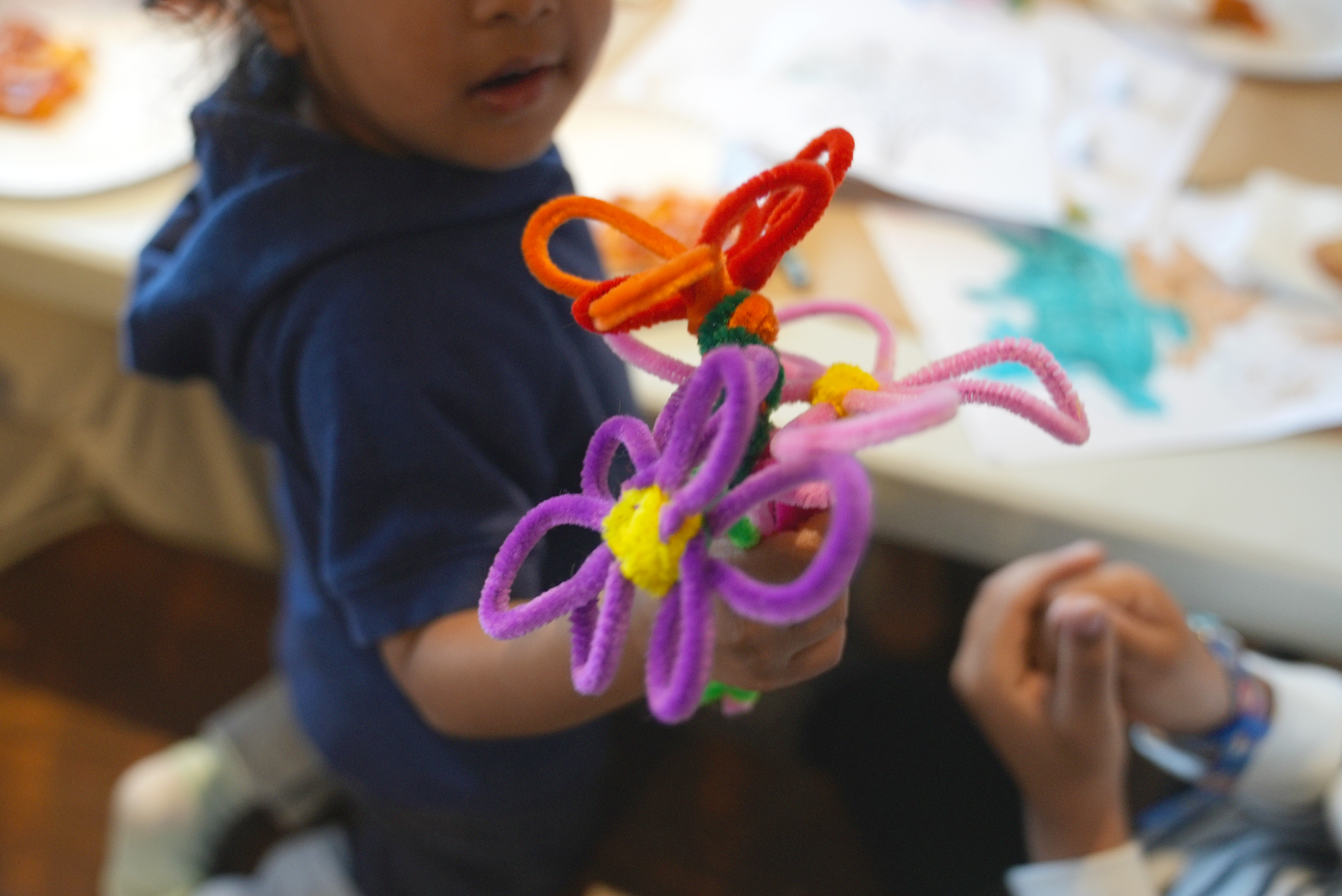 Child holds colourful pipe cleaners shaped into a bouquet of flowers at a March Break spring event at Album Studios.