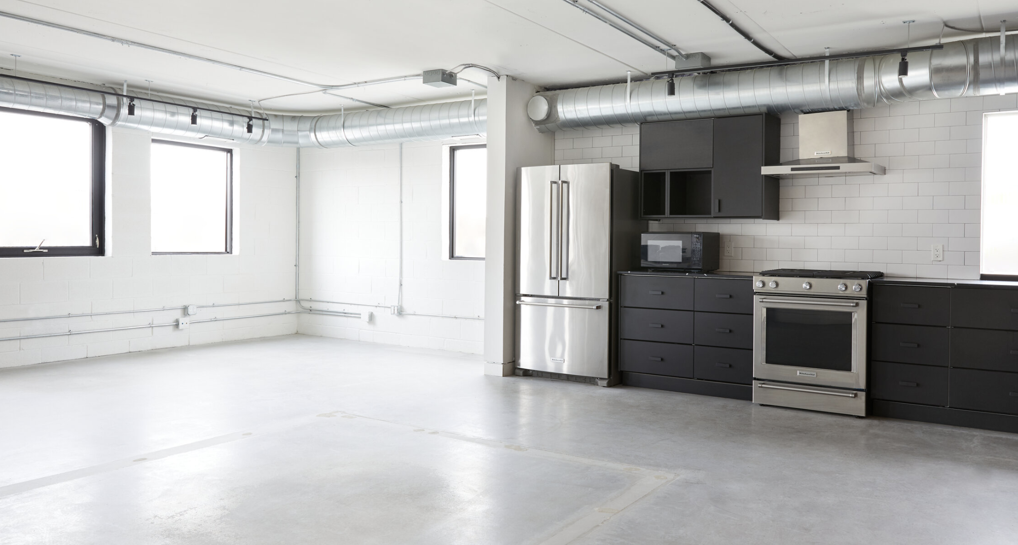 East and north facing windows. Bright, comfortable studio space with stainless steel kitchen appliances, stove and oven, range hood, refrigerator and freezer, and black counters and cupboards.