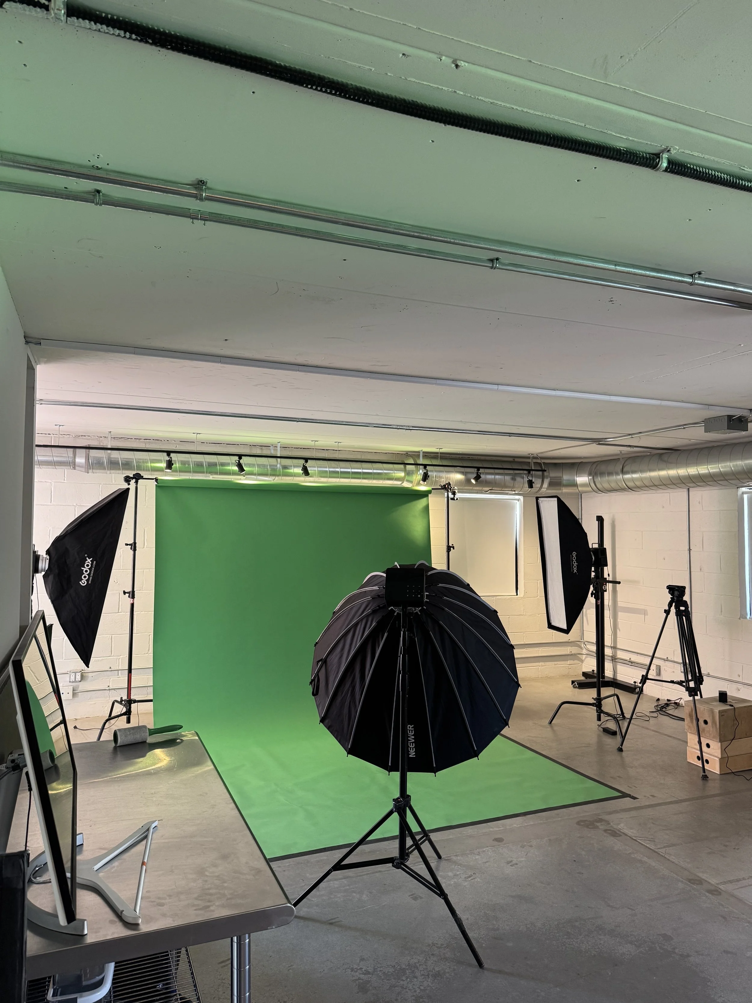 Photoshoot set up. Photography equipment includes Chroma green seamless backdrop with Godox lights, monitor, and apple boxes