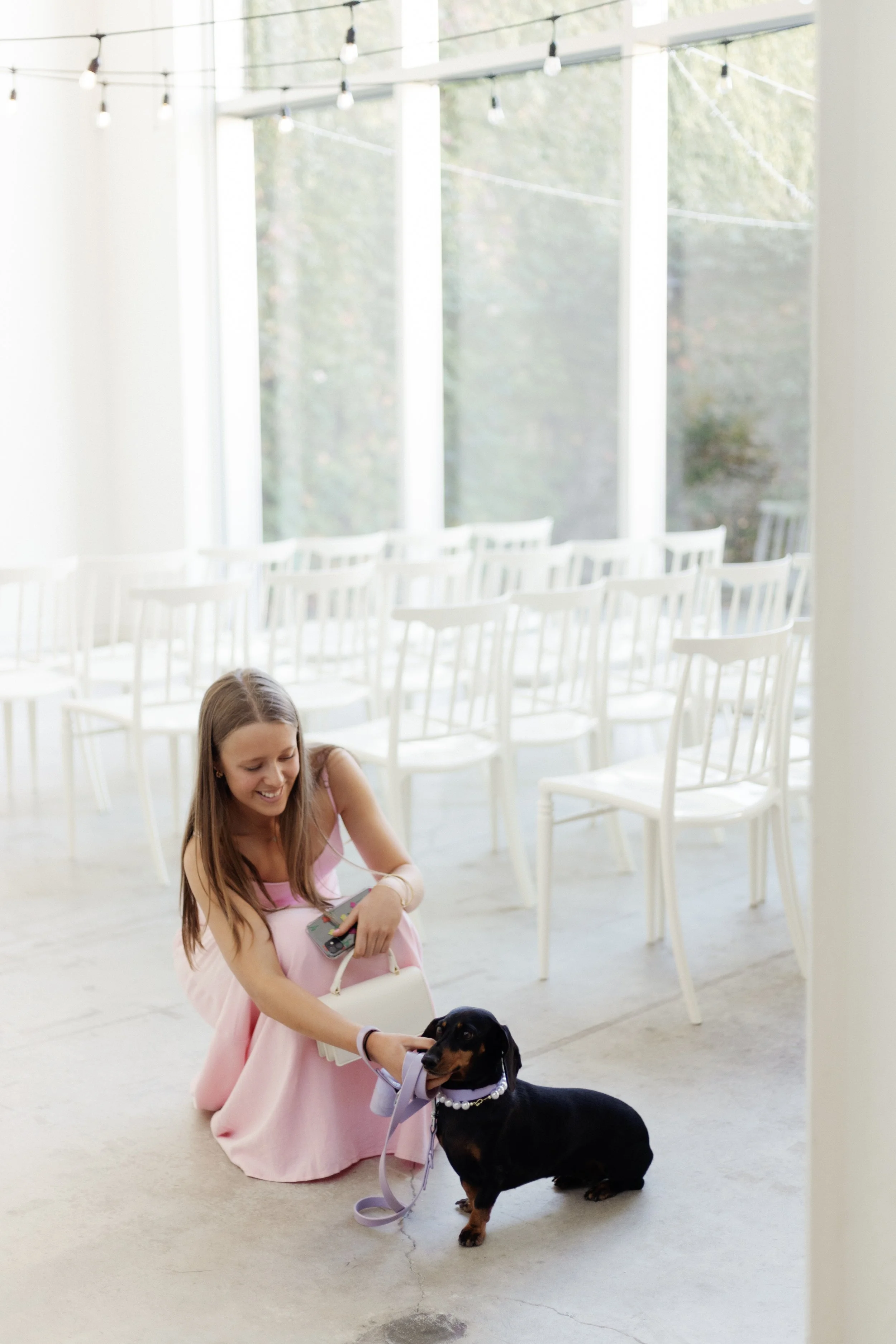 Dachshund and a wedding guest pose at the wedding ceremony held inside neutral toned event venue and studio space in Toronto