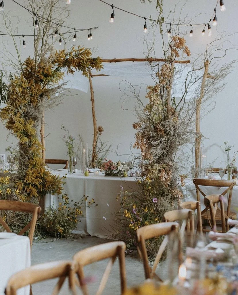 Organic and bohemian floral arch displayed during a seated wedding dinner inside a Toronto studio space and event venue rental