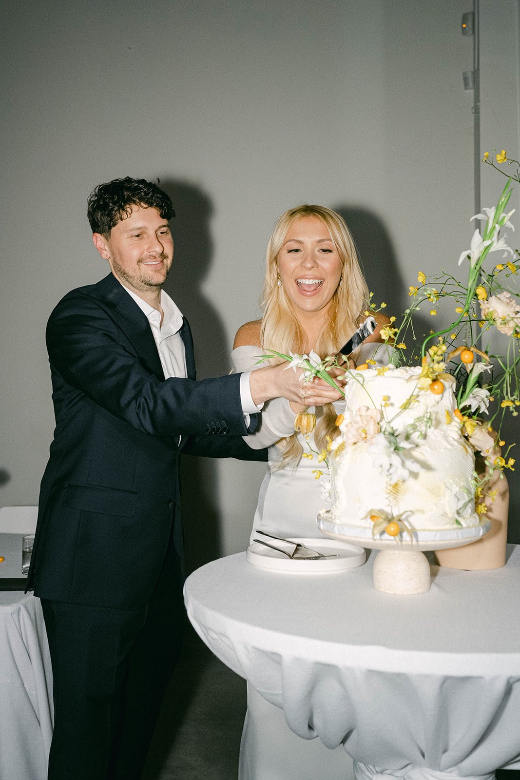 Bride and groom smiling while cutting their wedding cake