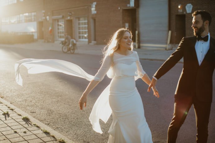 Bride and groom walking down the street during sunset 