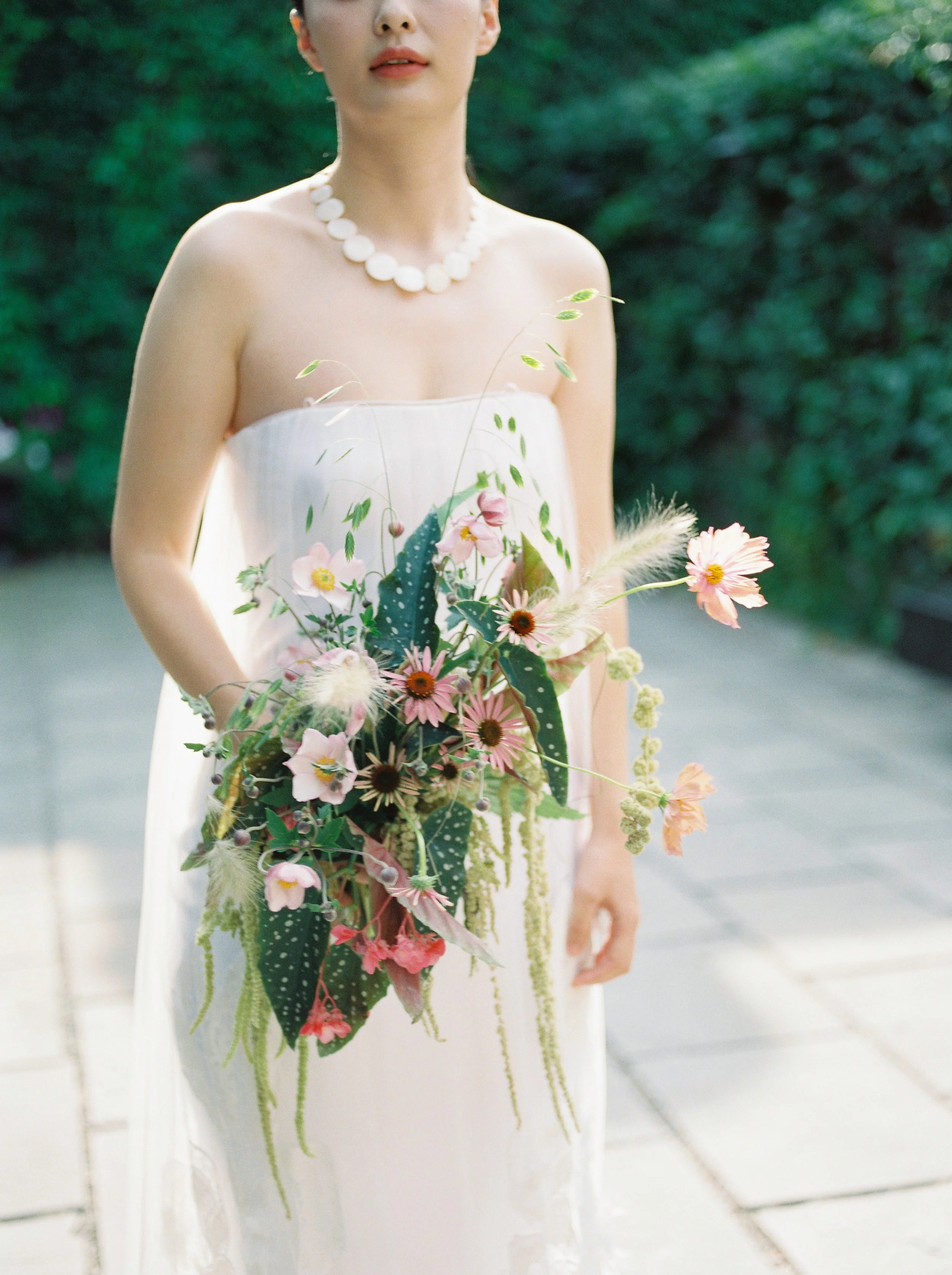 A bride poses in front of a Toronto event venue's private outdoor patio while holding a natural, organic wedding bouquet