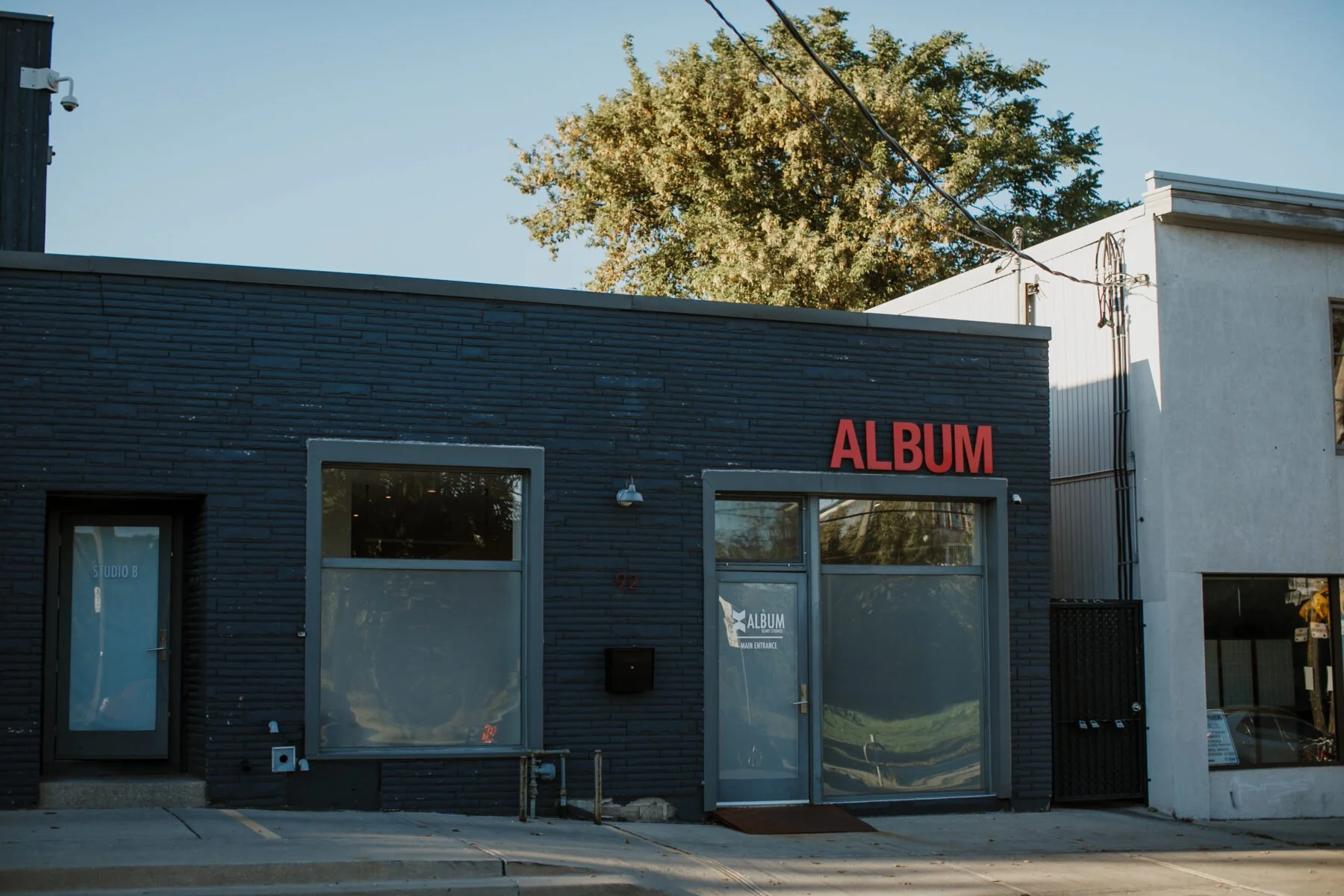 Front view of Album Studios building on 92 Geary Avenue in Toronto. The building is black and rectangular, with a large sign above the front door and windows that reads “Album” in capital letters.