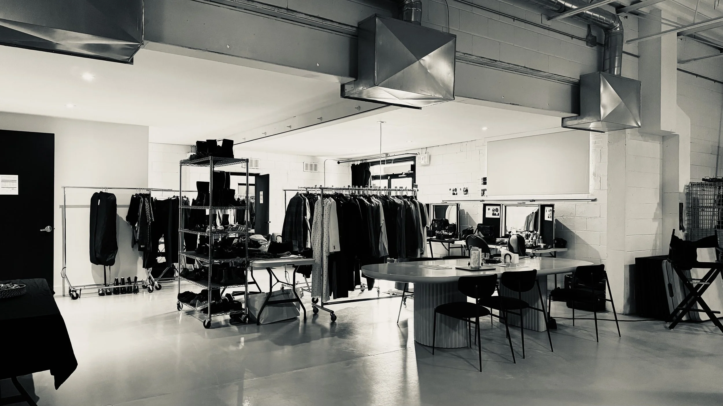 Behind-the-scenes wardrobe setup inside a spacious Toronto photography studio at Album Studios, with clothing racks, styling tables, makeup stations, and open production space.