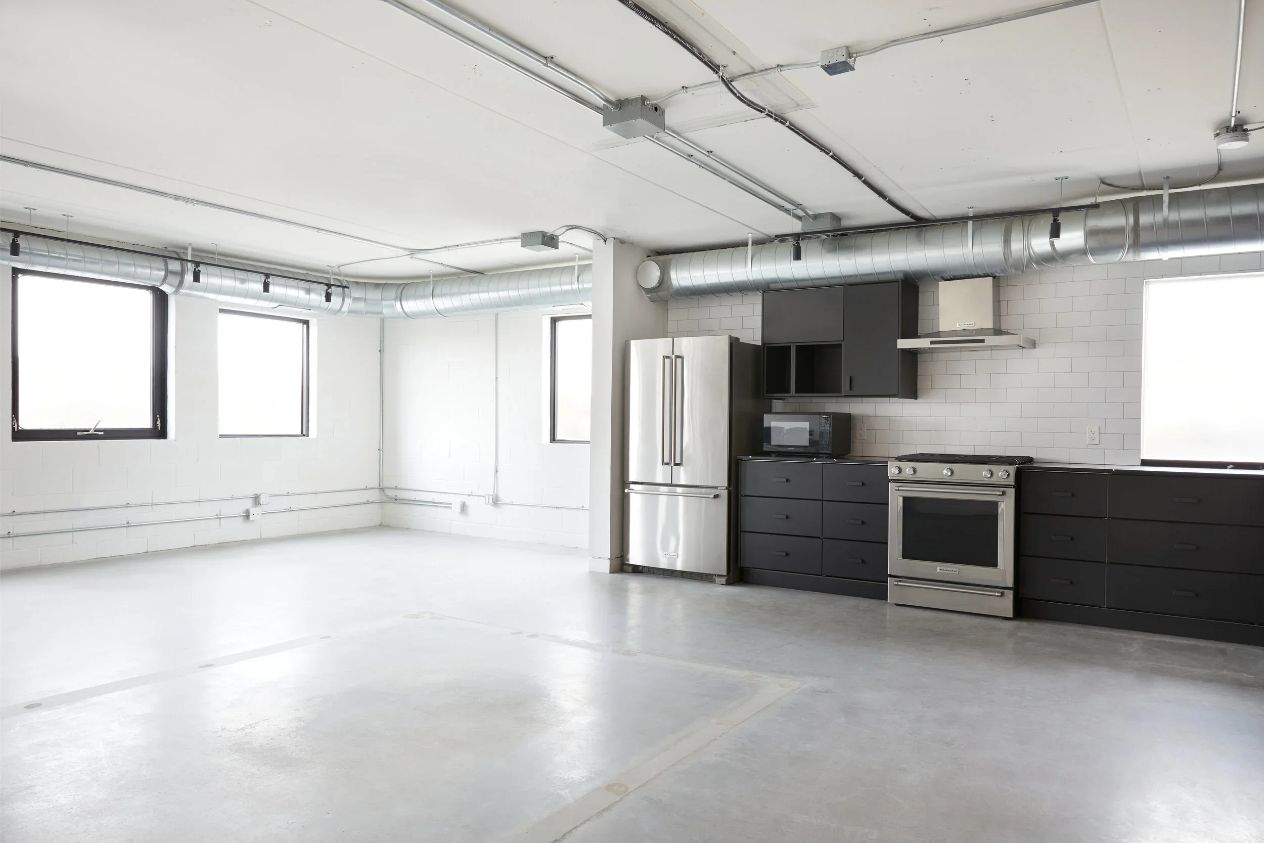 Loft style studio kitchen with sleek black cabinets and plenty of windows