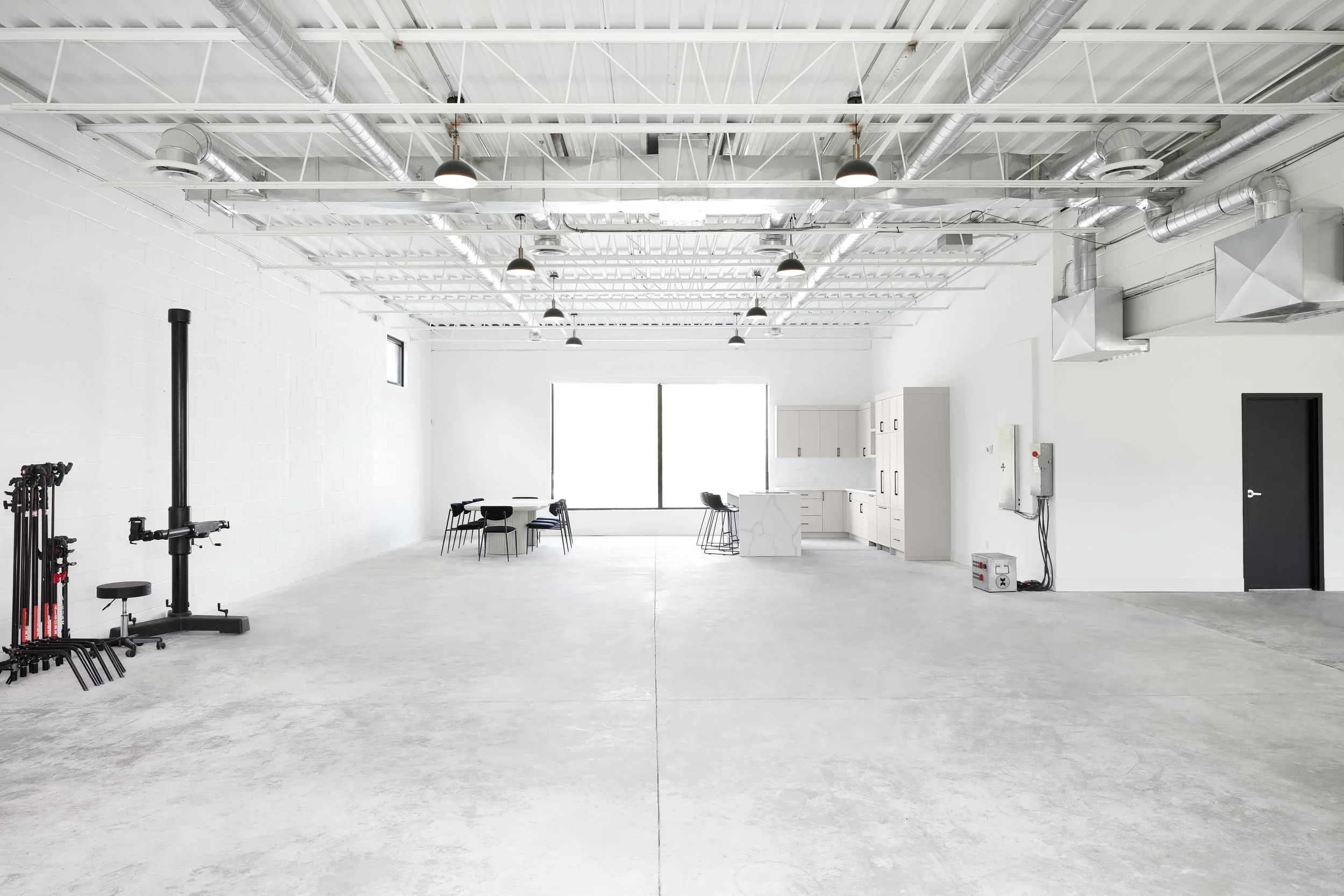 Spacious studio with natural light, cambo stands, c-stands, full kitchen, island stovetop, and dining table. 