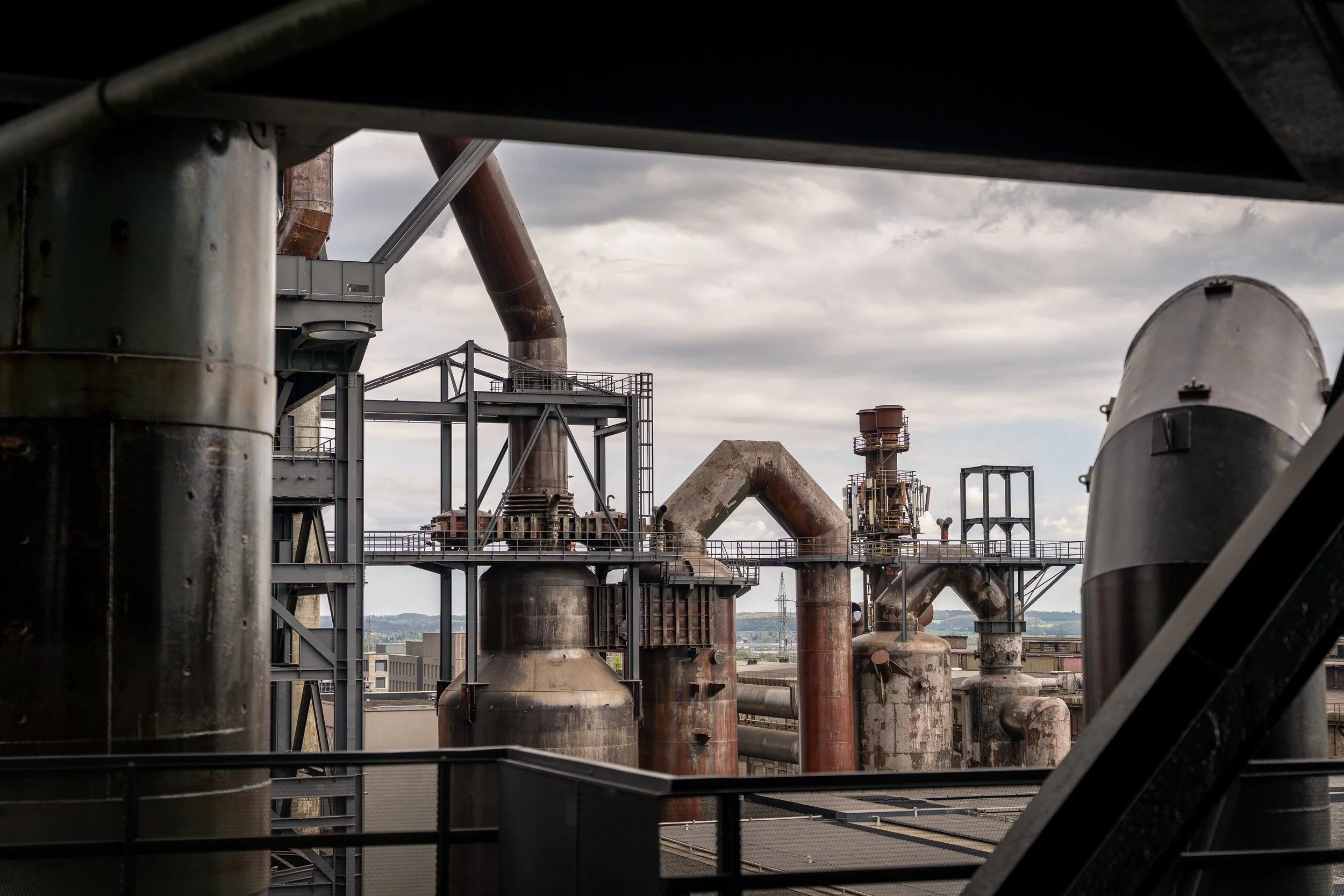 Industrieanlage mit Rohren und Tanks vor einem bewölkten Himmel
