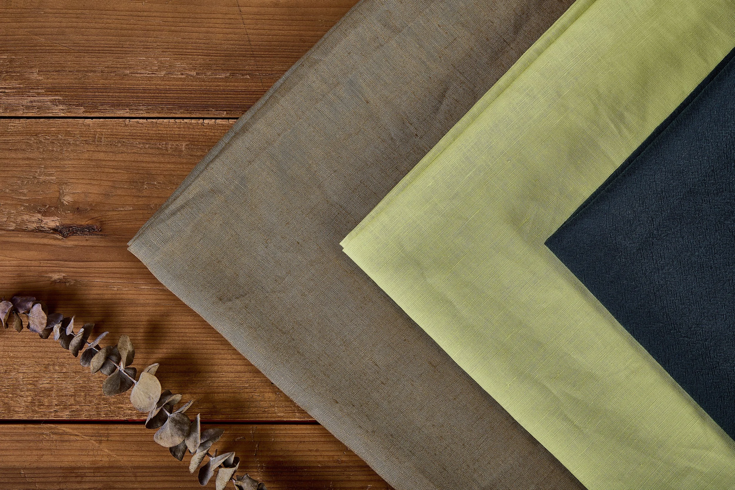 Neatly folded high-count woven linen fabric swatch samples on wooden board, free sample cards available from Novweave fabric exporter.