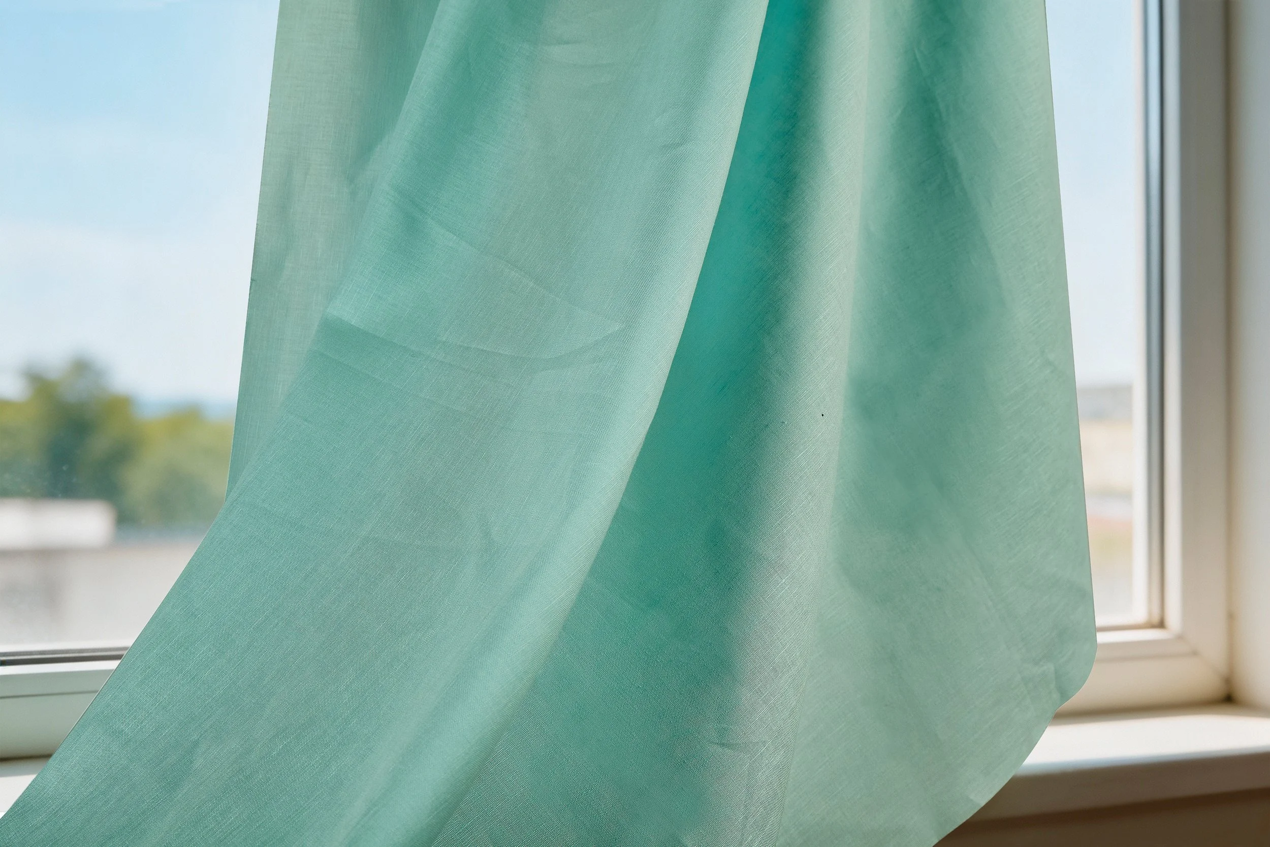 Sage green 55 linen 45 cotton lightweight blended fabric arranged in soft folds beside a contemporary lifestyle magazine.
