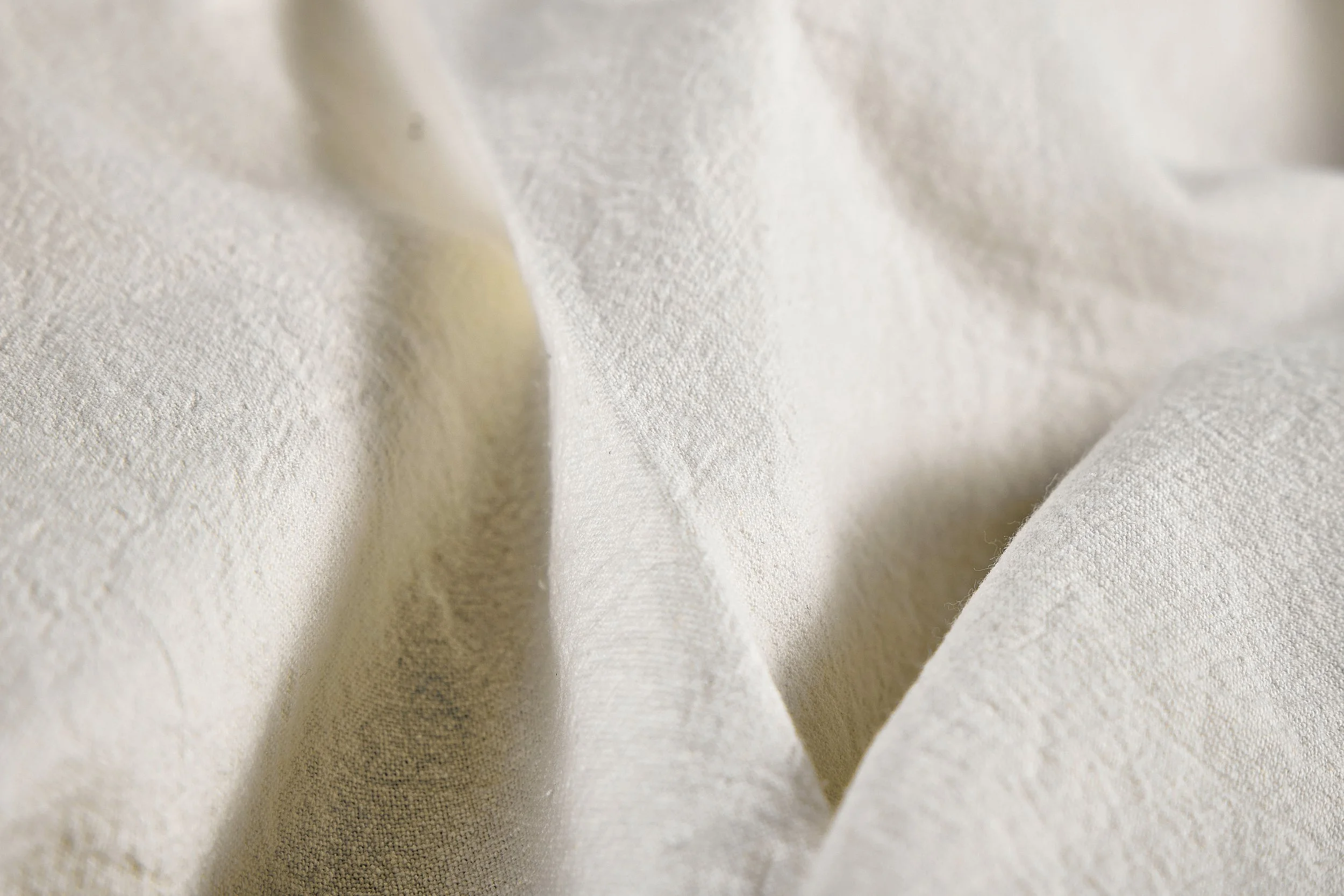 Close-up texture of ivory washed 30 linen 70 cotton fabric showing natural slub weave, breathability, and soft hand feel