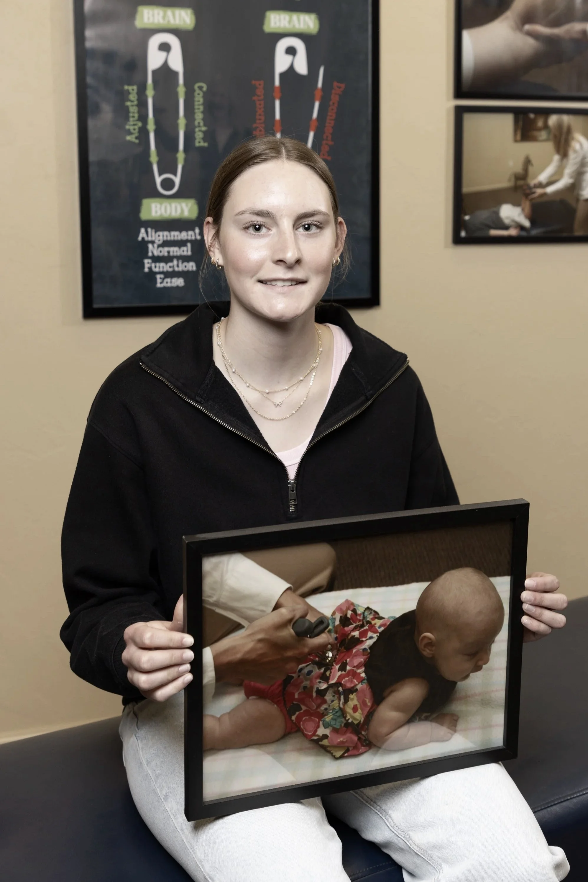 Longtime Miller Chiropractic patient holding a photo of herself receiving chiropractic care from Dr. Kay as a newborn.