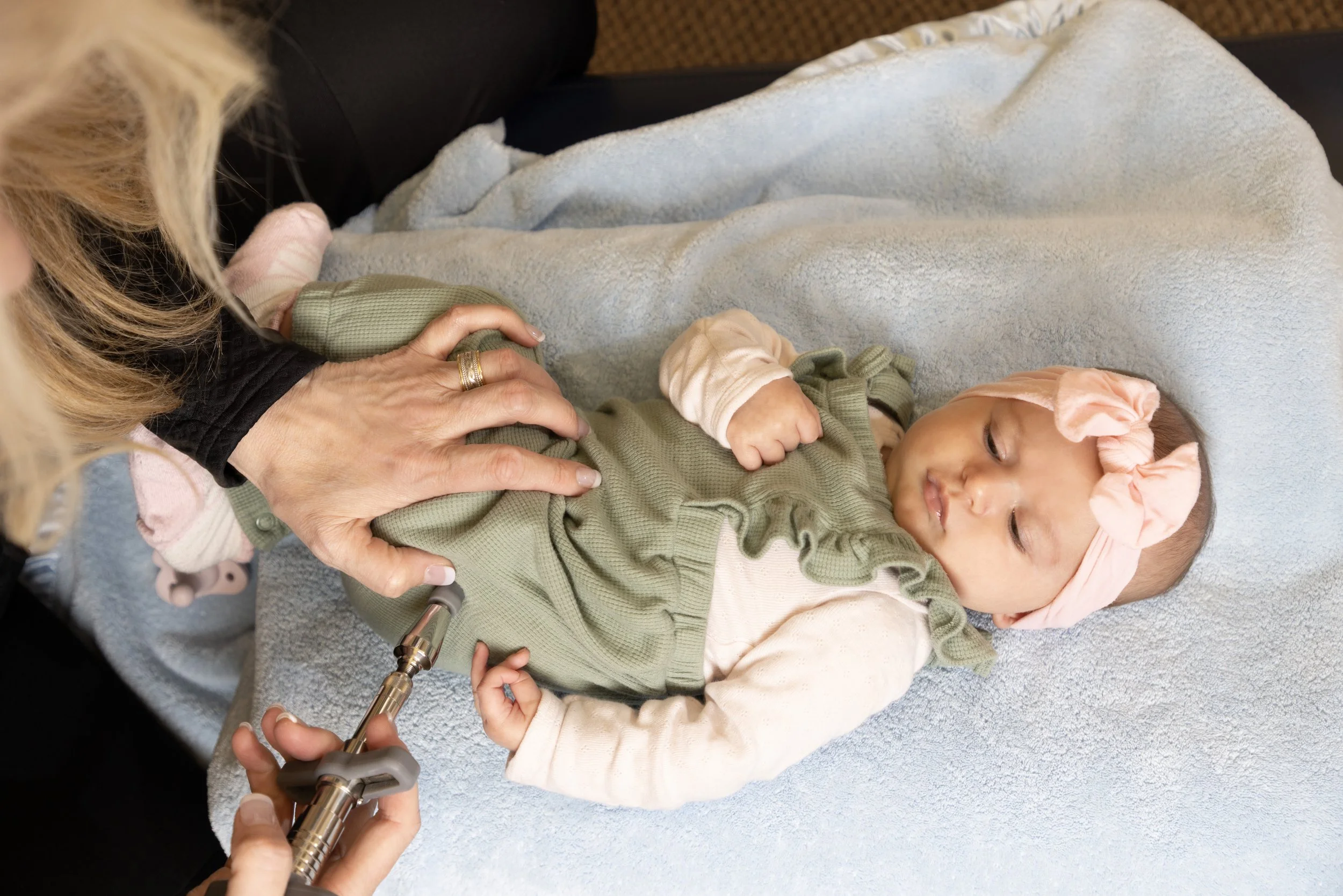 Dr. Kay Miller using an Activator instrument to provide chiropractic care to an infant.