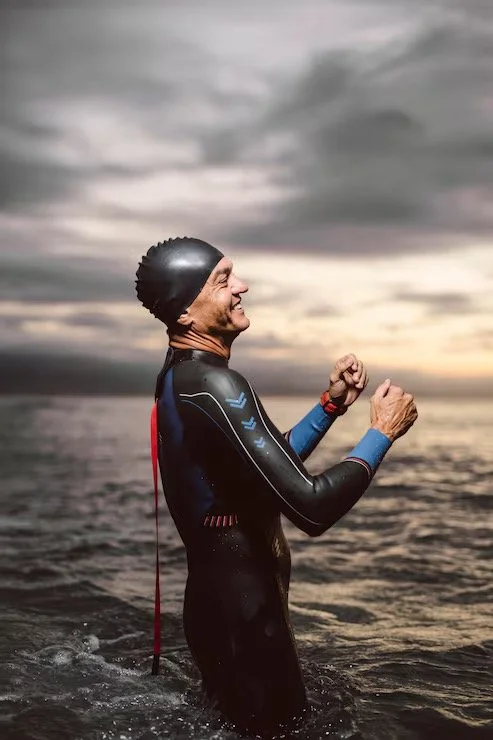 Triathlete standing in the water after a swim, representing sports injury and chiropractic care for active adults.