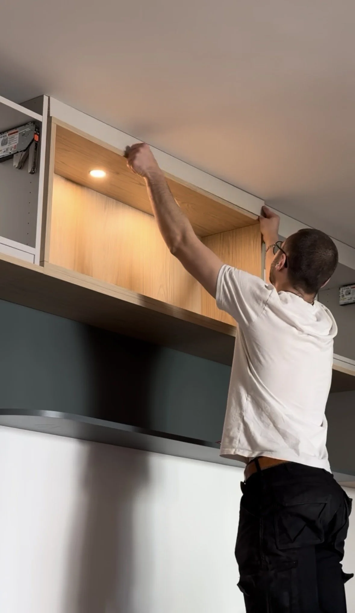 Un homme en train de fixer un panneau au plafond dans une pièce intérieure.